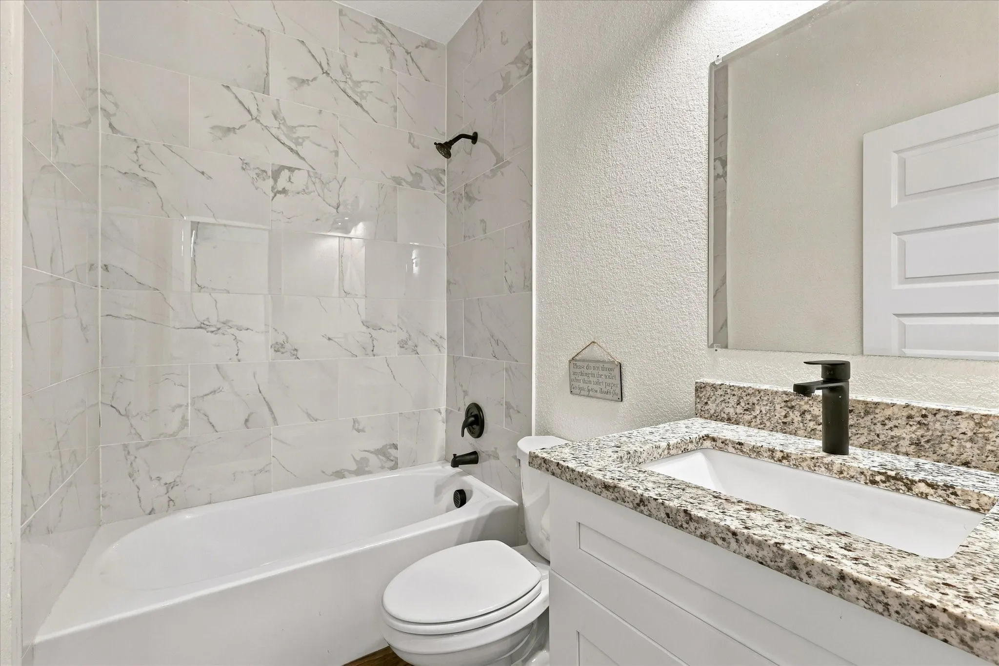 Bathtub with marble-look tile surround and matte black fixtures