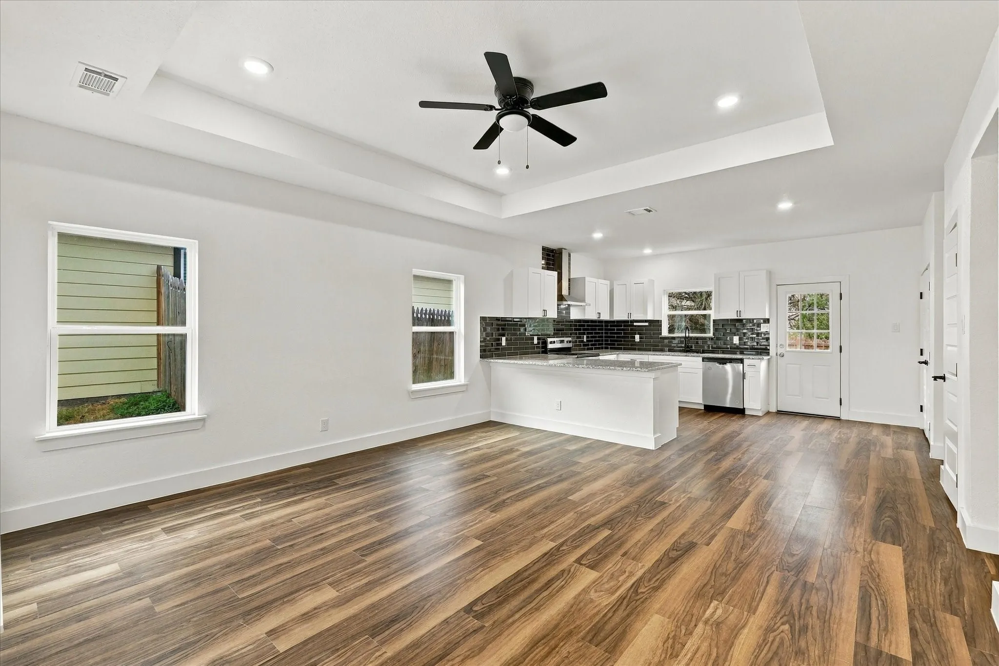 Open-concept living and kitchen area showcasing refinished wood flooring, recessed ceiling lighting, and a ceiling fan
