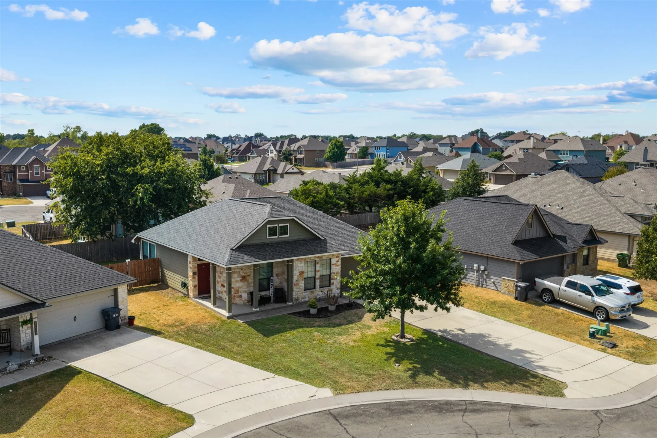 Pitched rooflines, partial stone facade, covered entry, and concrete driveway