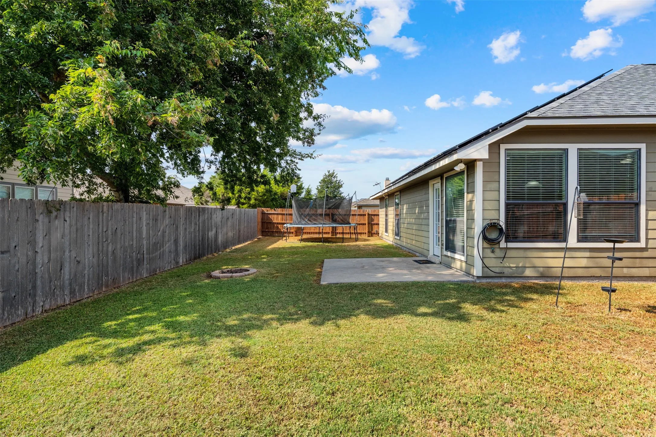 Expansive backyard with a manicured lawn, wood privacy fencing, and a concrete patio