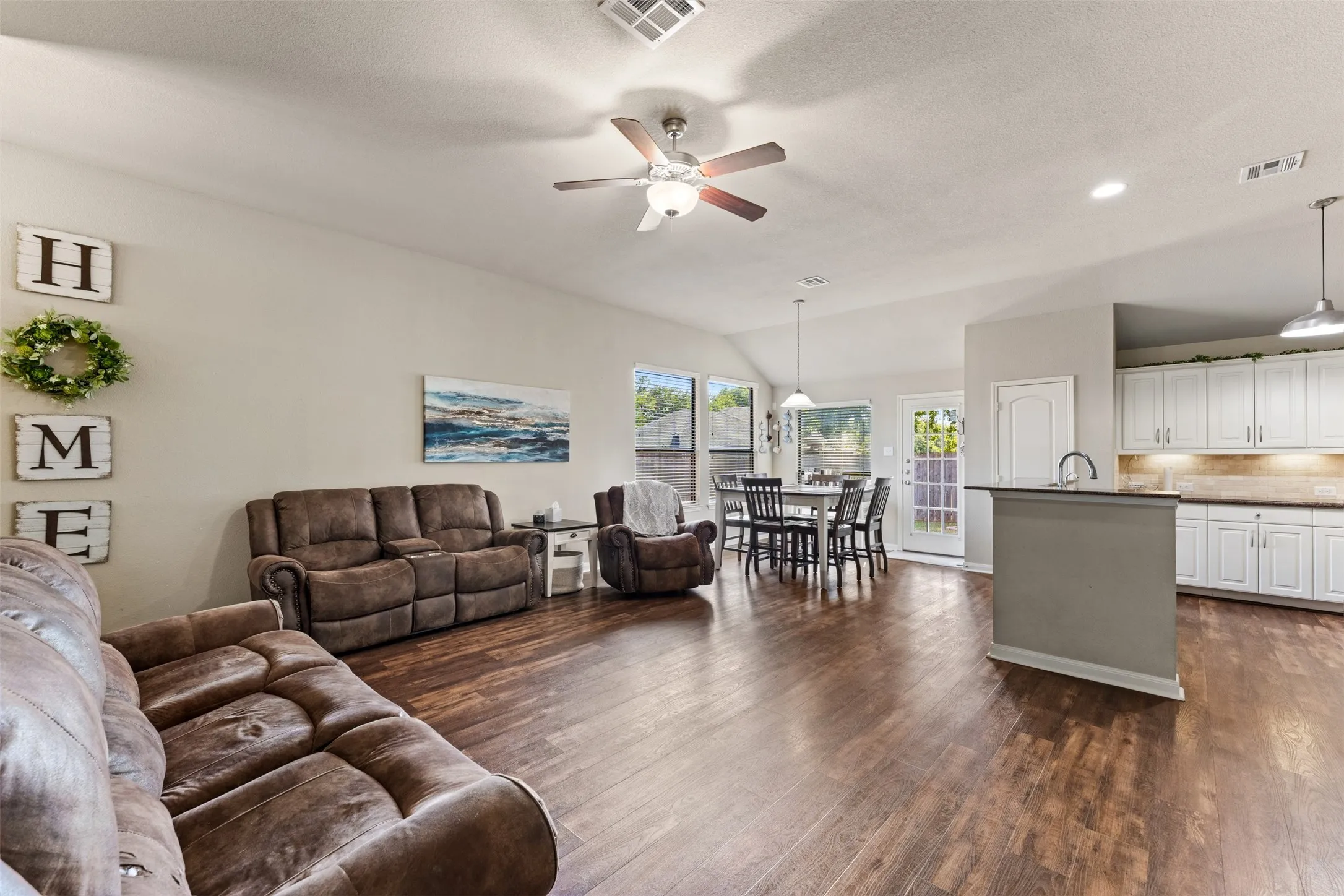 Open-concept living space featuring wood-finish flooring, vaulted ceilings, and recessed lighting