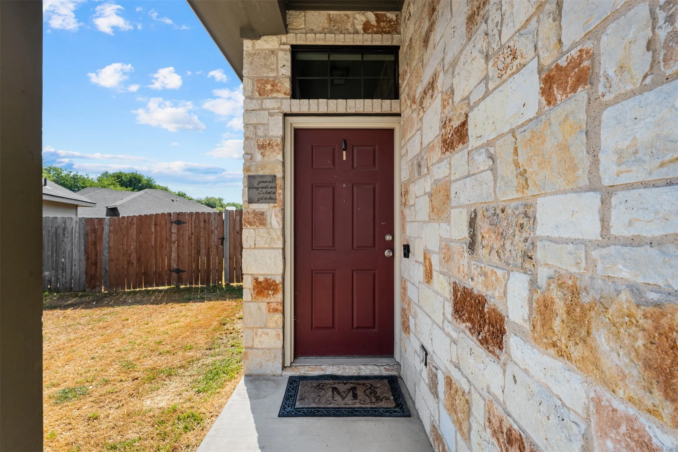 Stone veneer exterior, solid wood entry door, and concrete porch