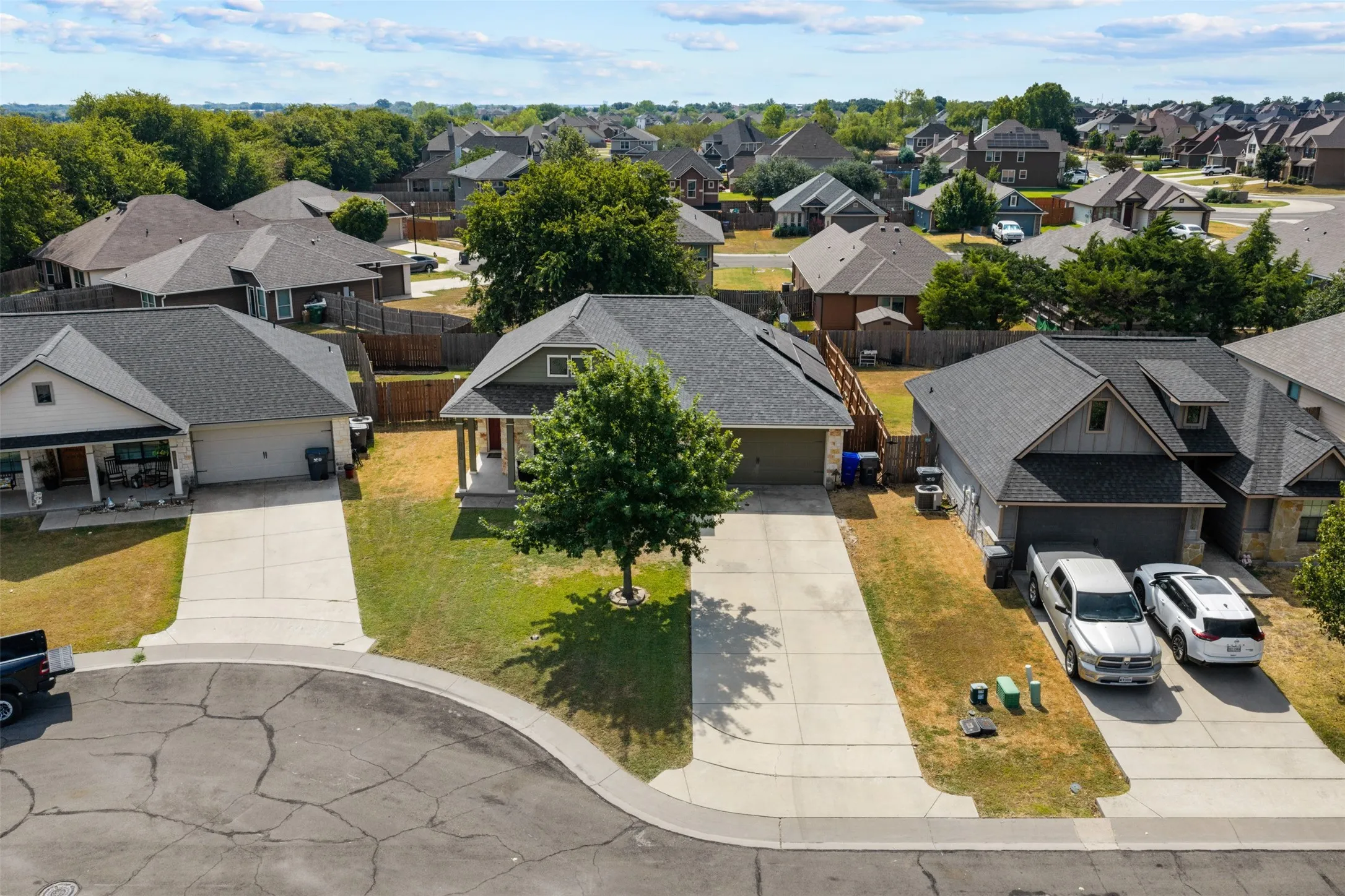 Cul-de-sac property featuring a gabled roofline, attached two-car garage, and an extra long concrete driveway