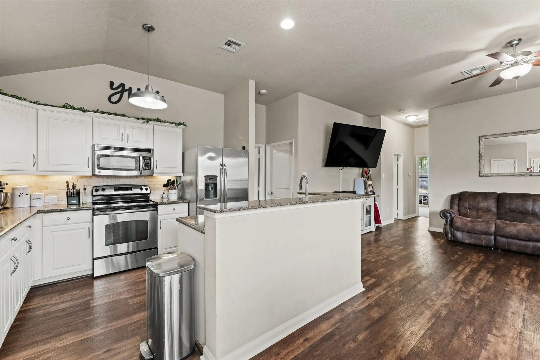 Kitchen featuring white cabinetry, stainless steel appliances, granite countertops, and wood-finish flooring