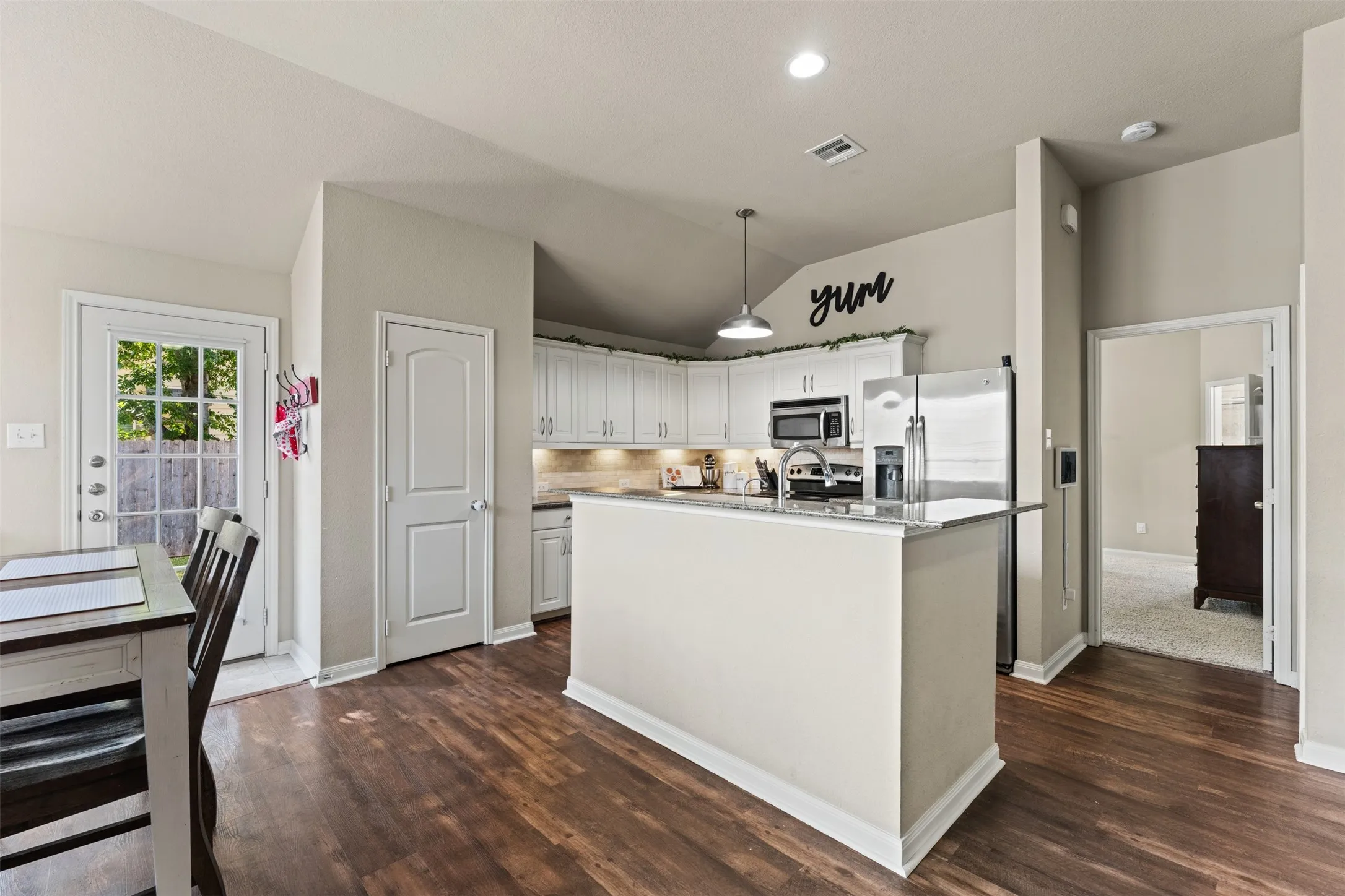 Kitchen featuring white cabinetry, stainless steel appliances, a kitchen island with a stone-finish countertop, wood-finish flooring, and recessed lighting
