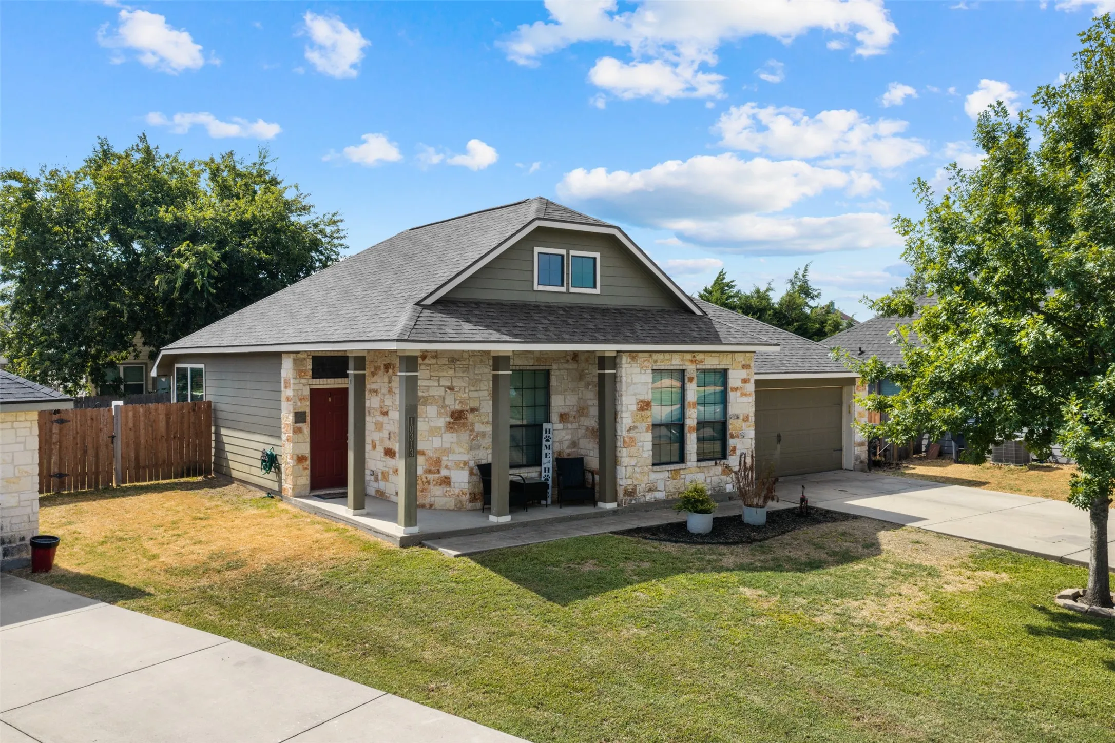 Stone and siding exterior with a covered porch, a two-car garage, and a concrete driveway