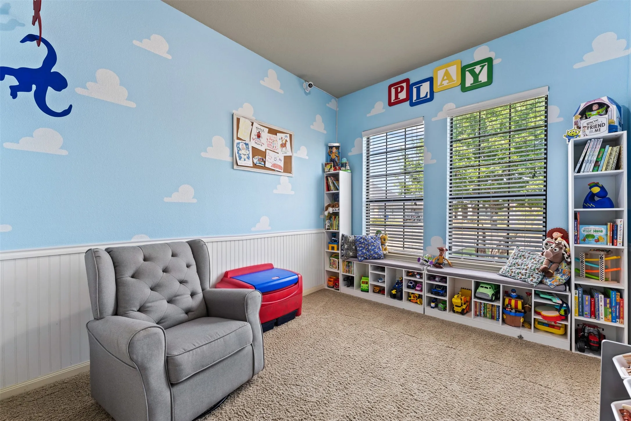 Room featuring two windows with blinds, built-in shelving, white wainscoting, and carpeted flooring