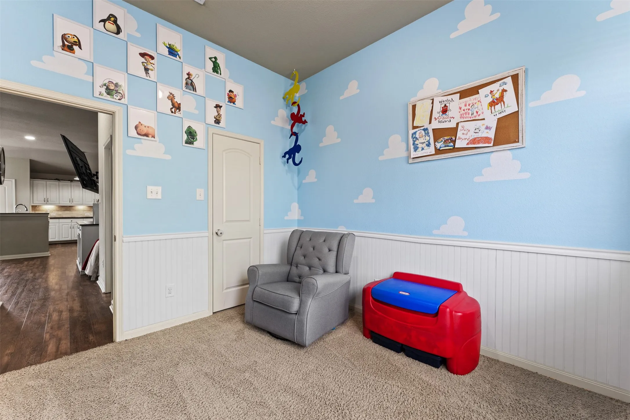 Carpeted room featuring white wainscoting and a solid core door