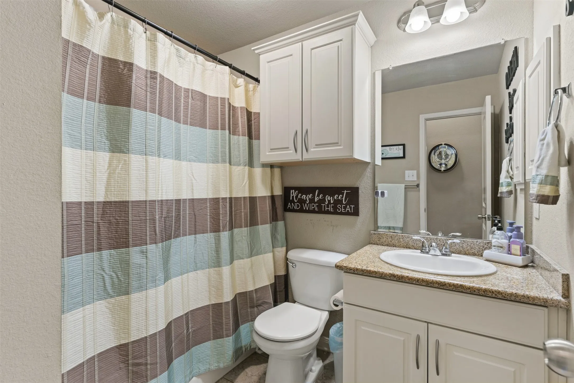 Vanity with a granite-style countertop, white cabinetry, and a drop-in sink