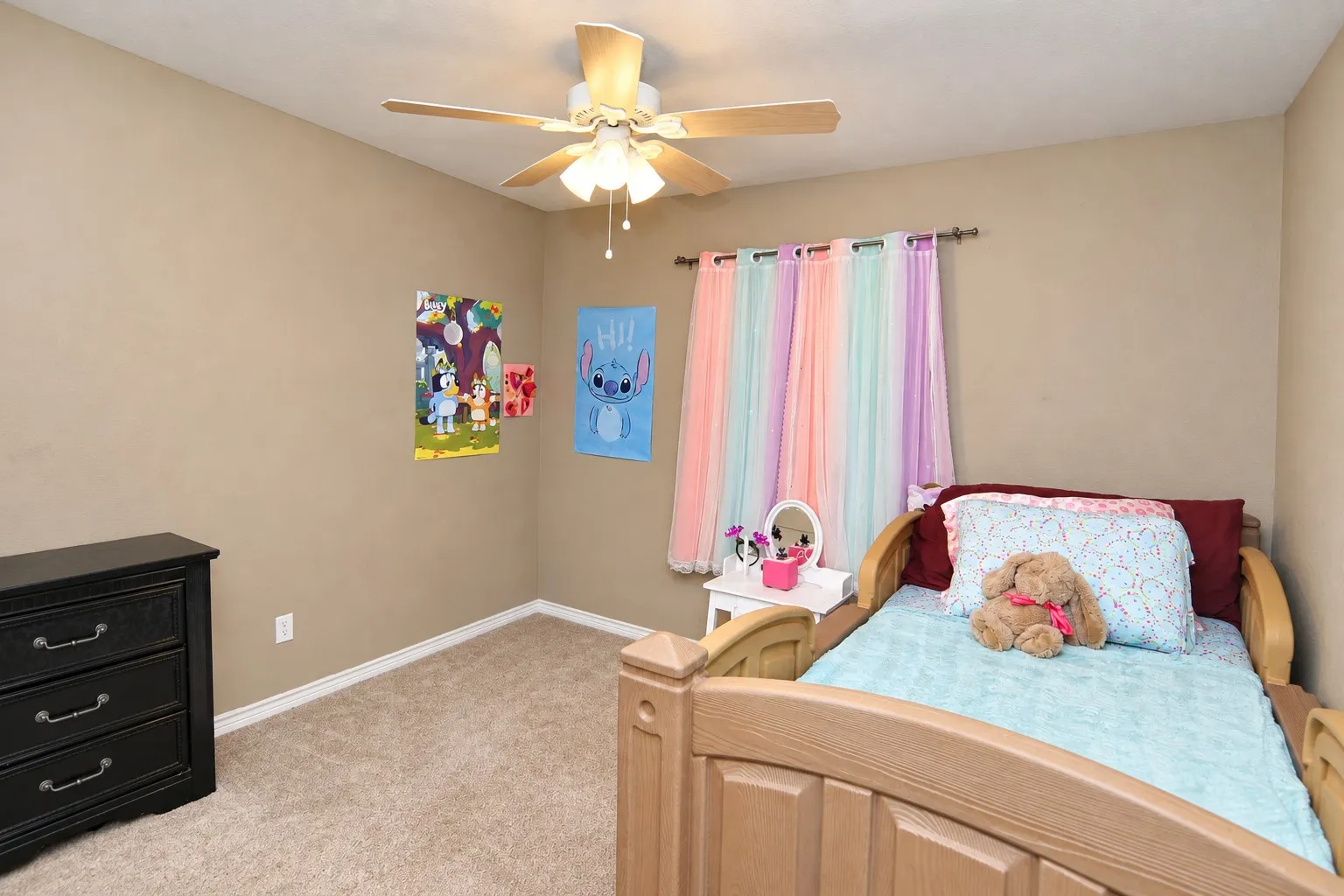 Carpeted flooring, neutral wall color, ceiling fan with light fixture, window with drapery rod, built-in dresser