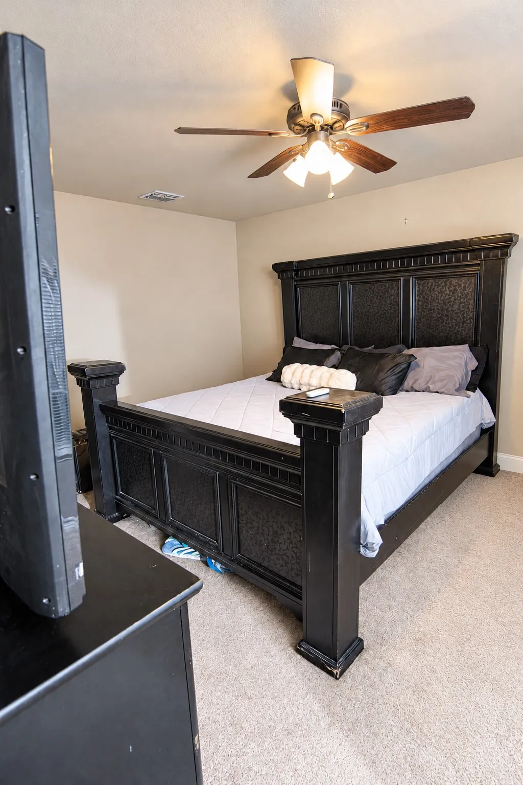 Textured carpeting, neutral wall paint, and a ceiling fan with integrated lighting