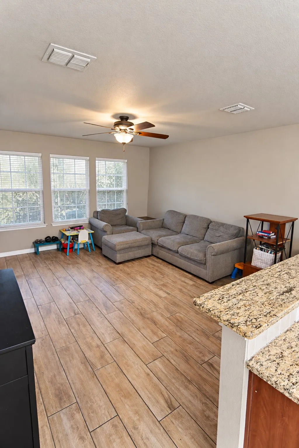 Spacious living area featuring wood-finish flooring and a ceiling fan