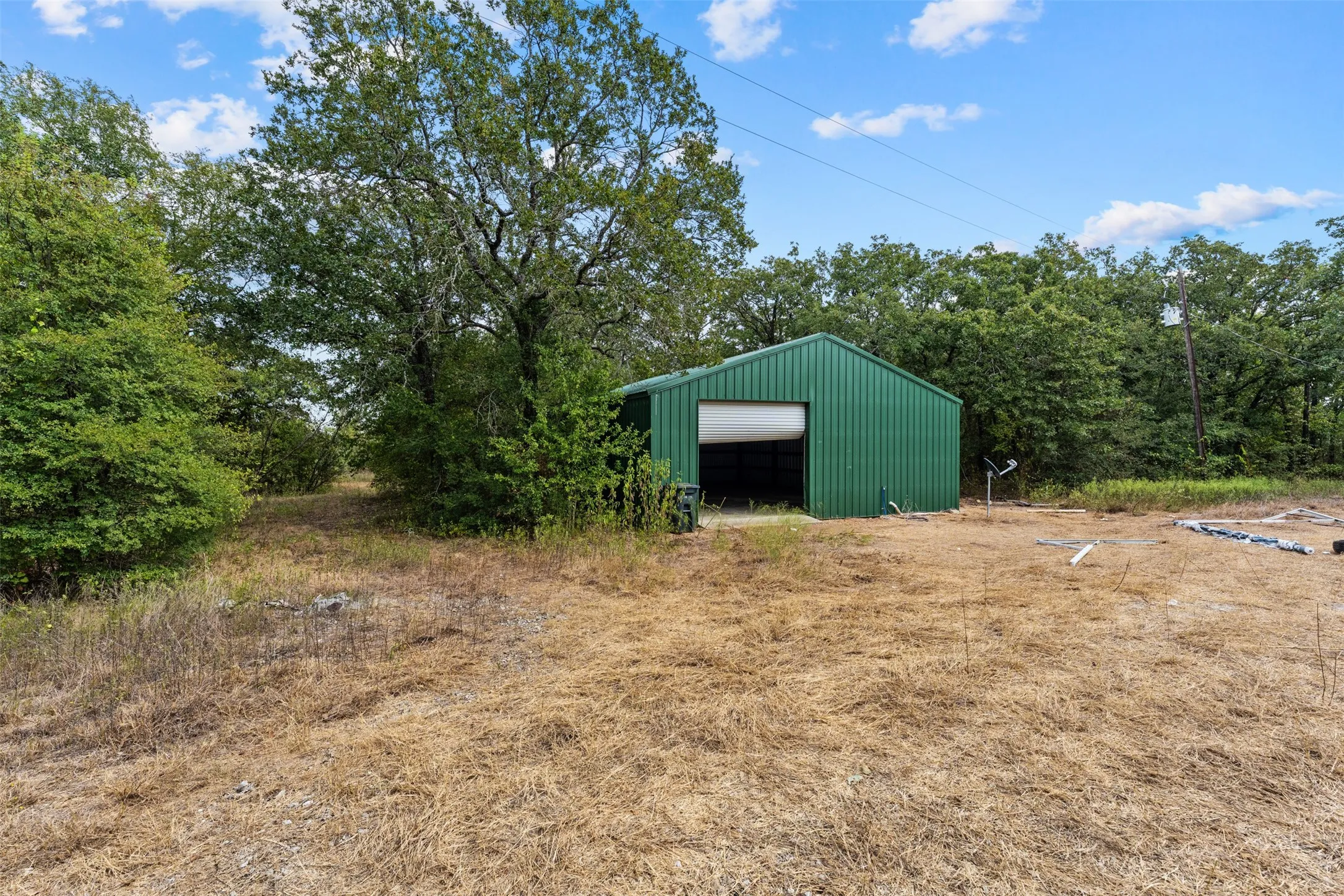 Green metal-sided utility building with a roll-up door