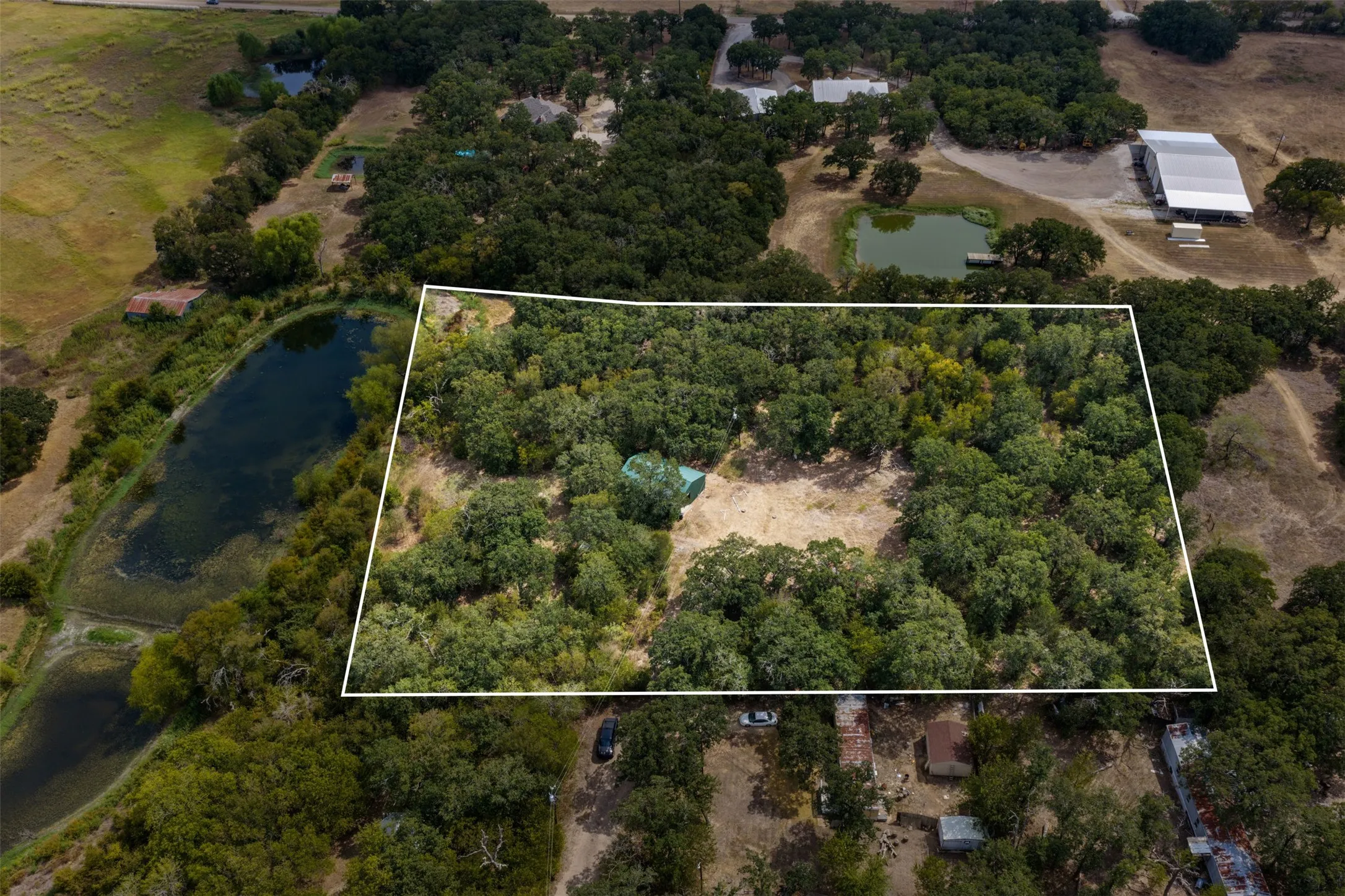 Expansive wooded acreage featuring a cleared building site and a single-story dwelling