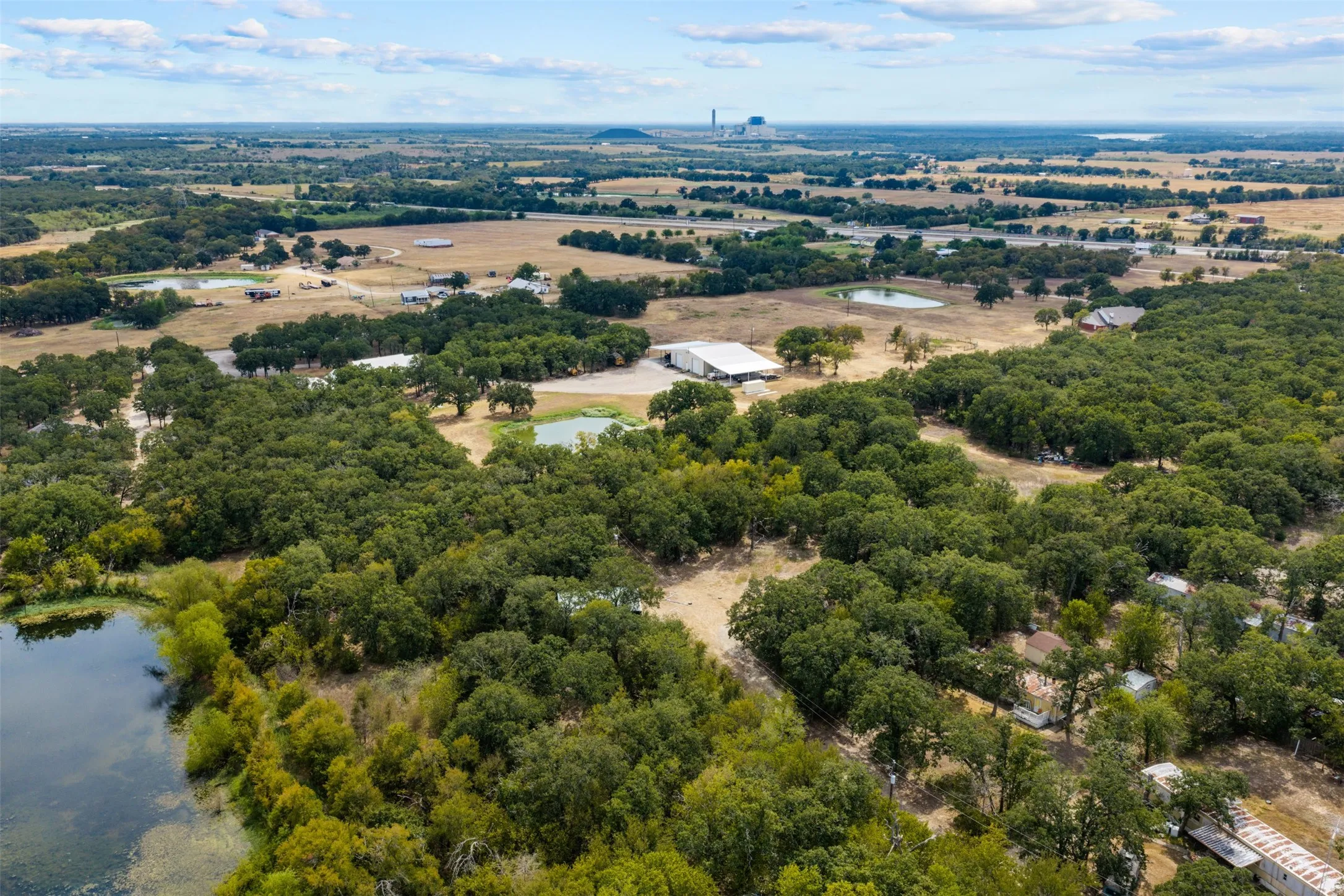 Expansive acreage featuring mature trees, a natural pond, and distant open fields