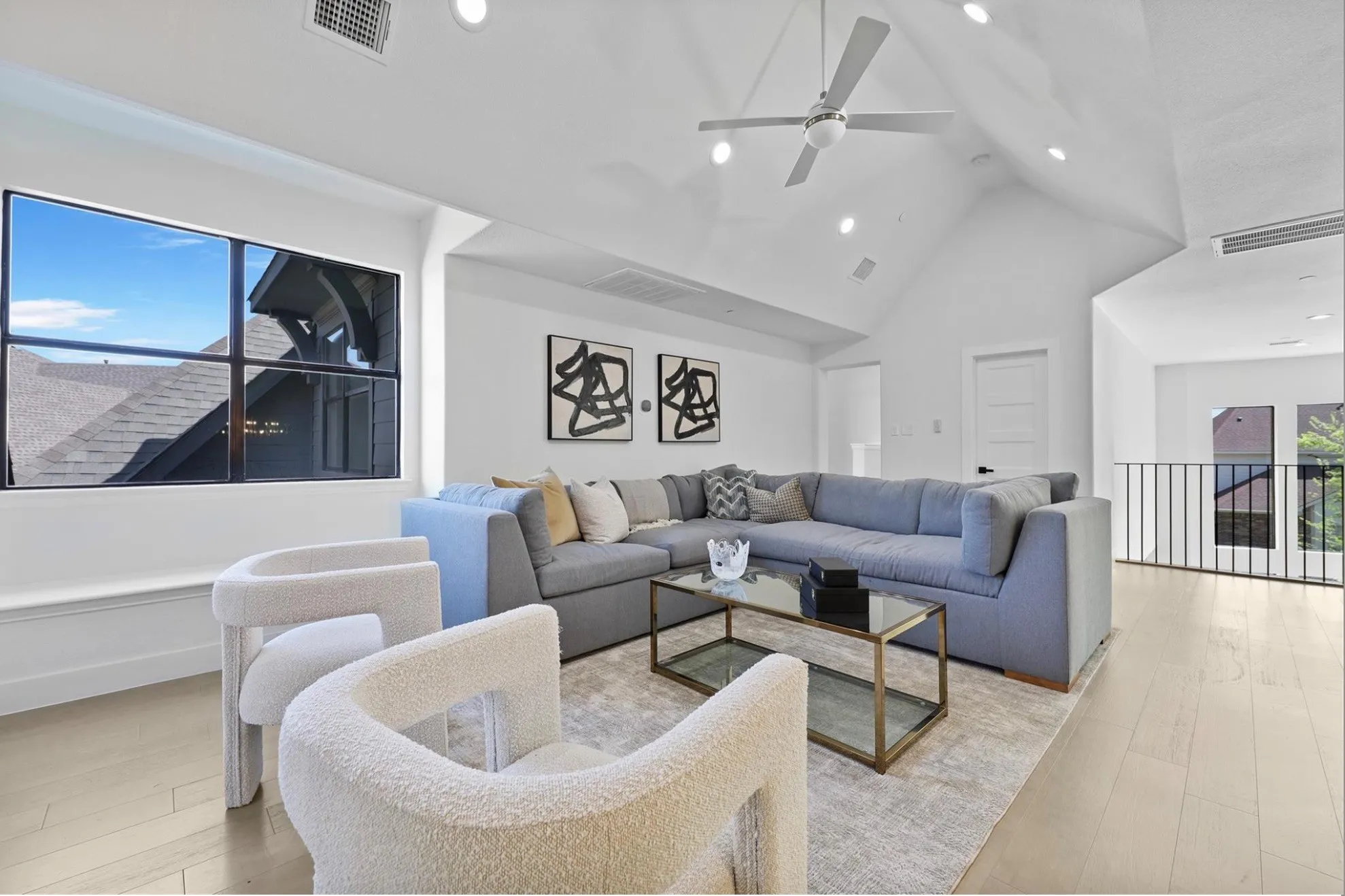 Vaulted ceiling featuring a ceiling fan and recessed lighting, light wood-finish flooring, and a black metal railing
