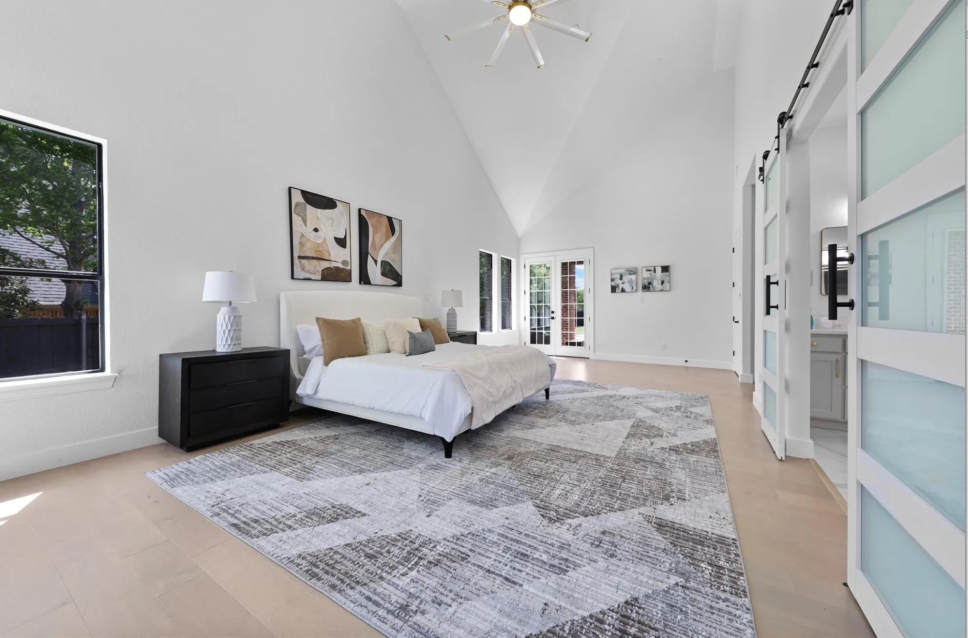 Vaulted ceiling with a ceiling fan, light wood-finish flooring, and double French doors
