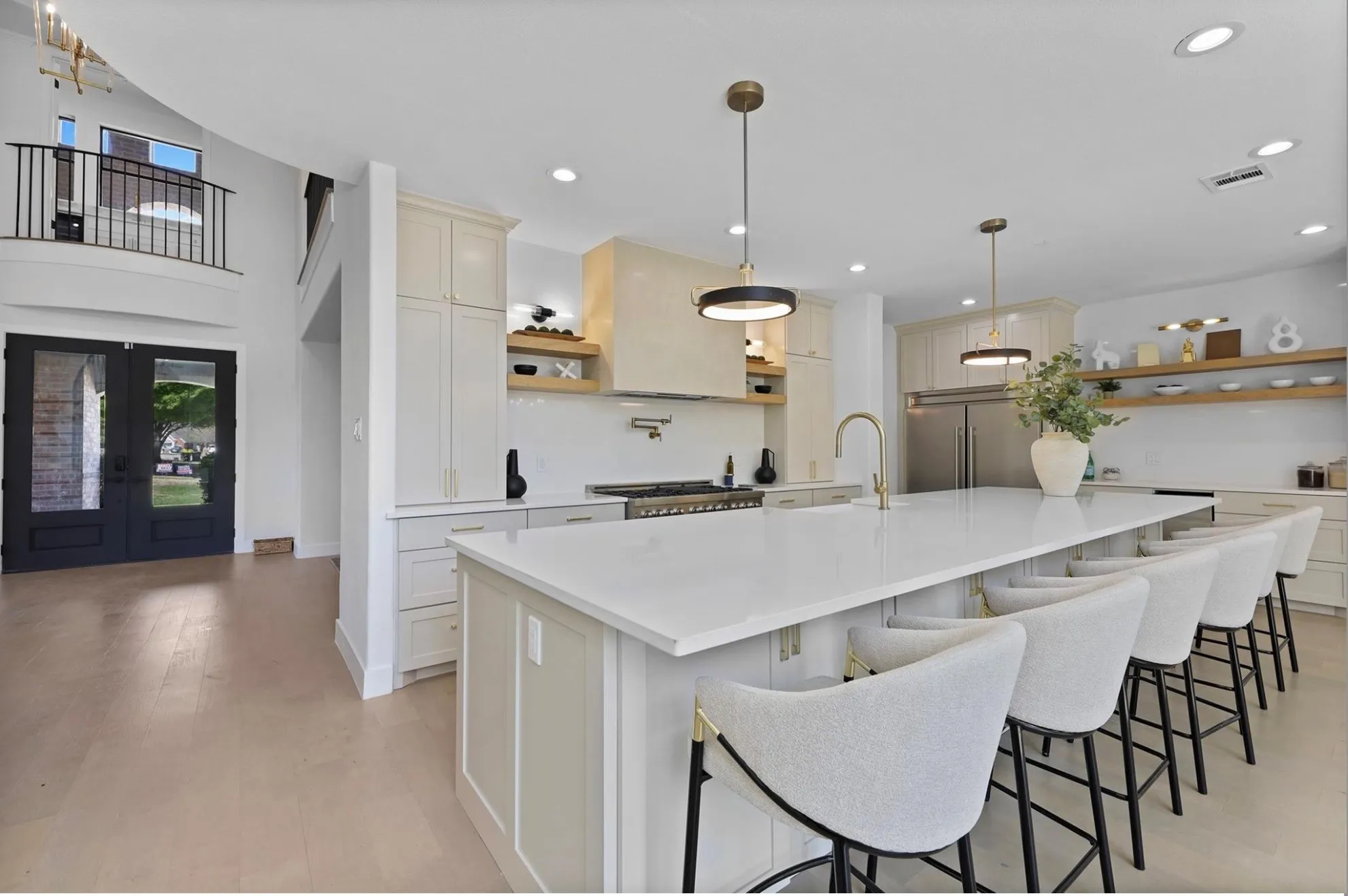 Spacious kitchen with a large central island, integrated appliances, and open shelving
