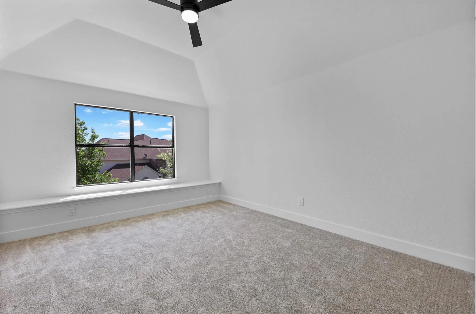Vaulted ceiling room featuring a multi-pane window, integrated window bench, and a ceiling fan