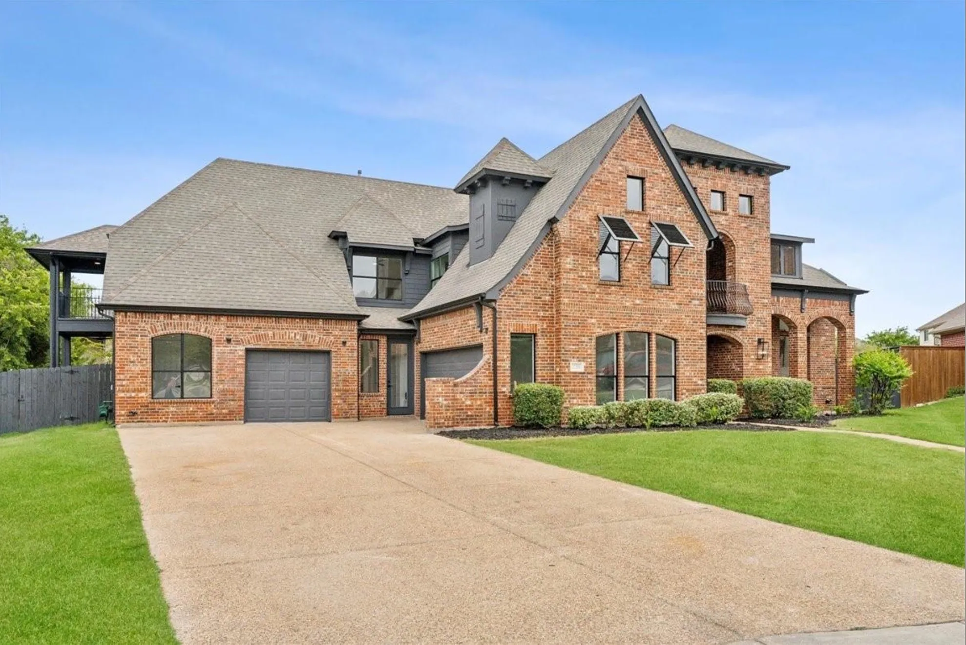 Brick exterior with multiple architectural elements, a two-car garage, and a concrete driveway