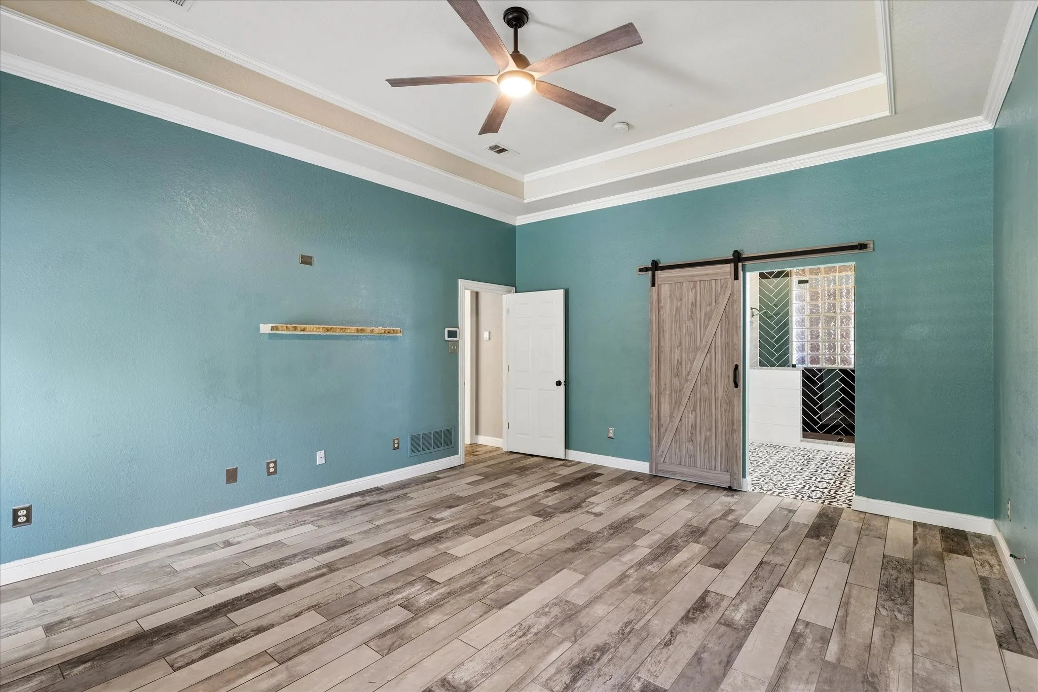 Spacious interior with wood-finish flooring, a tray ceiling, and a ceiling fan