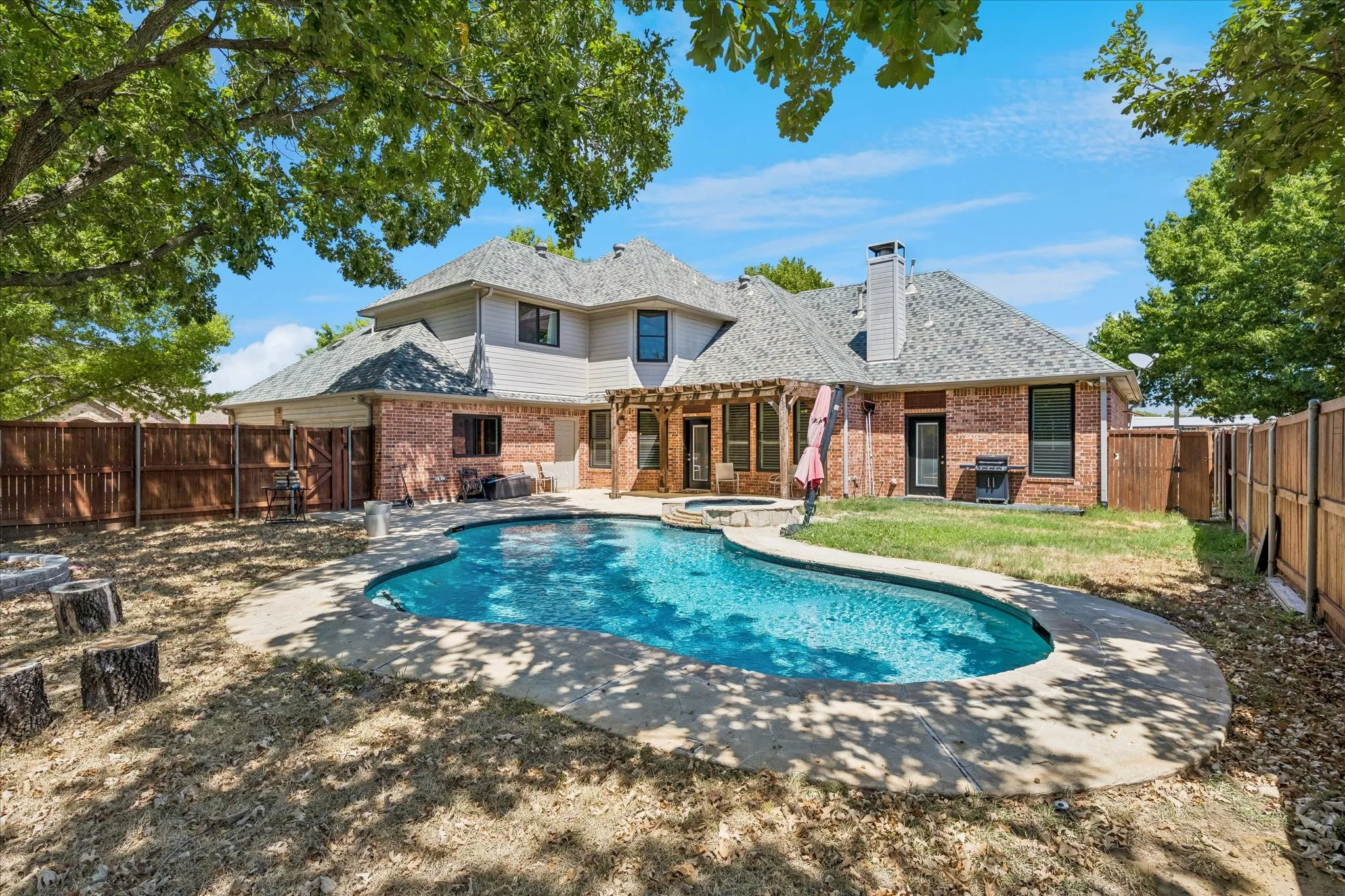 Brick exterior with a multi-level roofline, in-ground swimming pool, and an attached spa