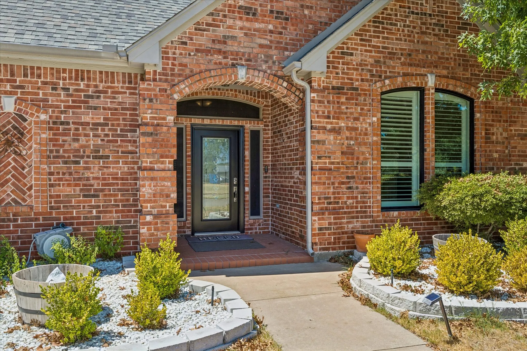 Brick exterior with decorative herringbone detail, arched entryway, glass-paneled front door, and a curved walkway