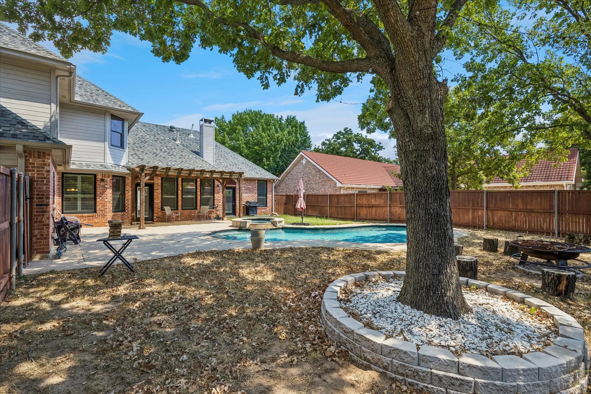 Expansive backyard featuring a swimming pool, paved patio, and a shaded pergola