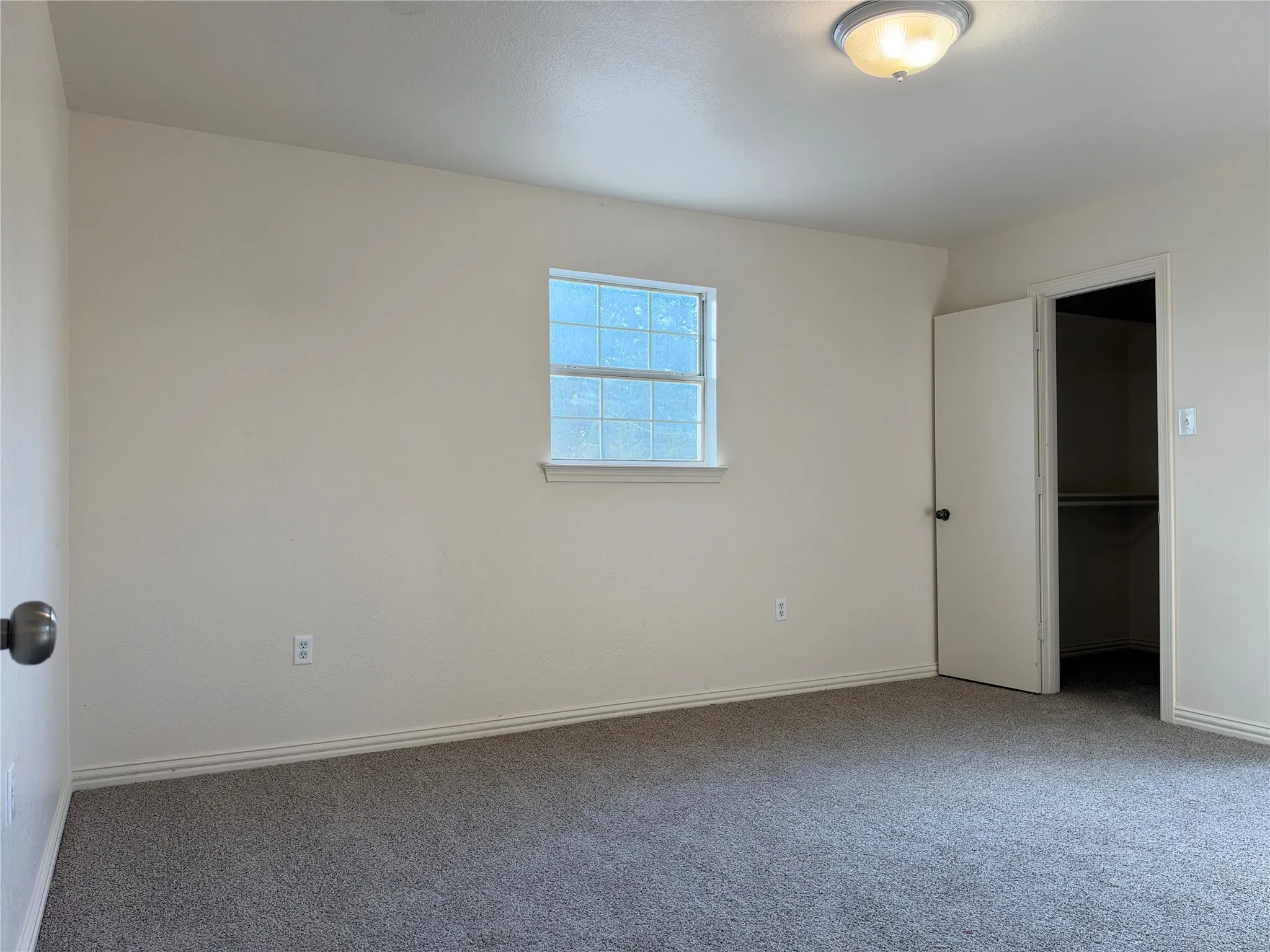 Recessed window, ceiling-mounted light fixture, and gray carpeted flooring