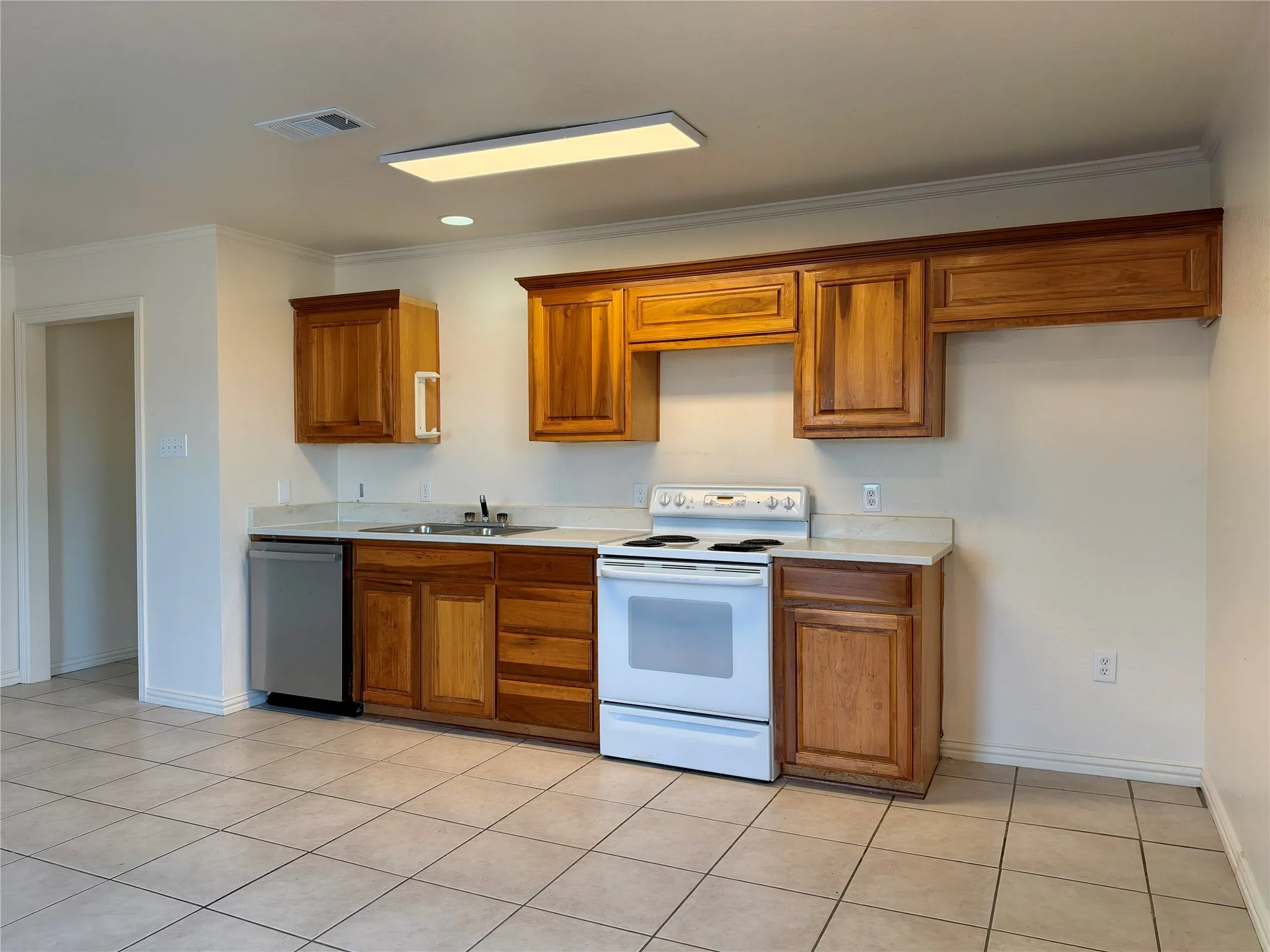 Kitchen featuring light wood-finish cabinetry, tile flooring, and a stainless steel dishwasher