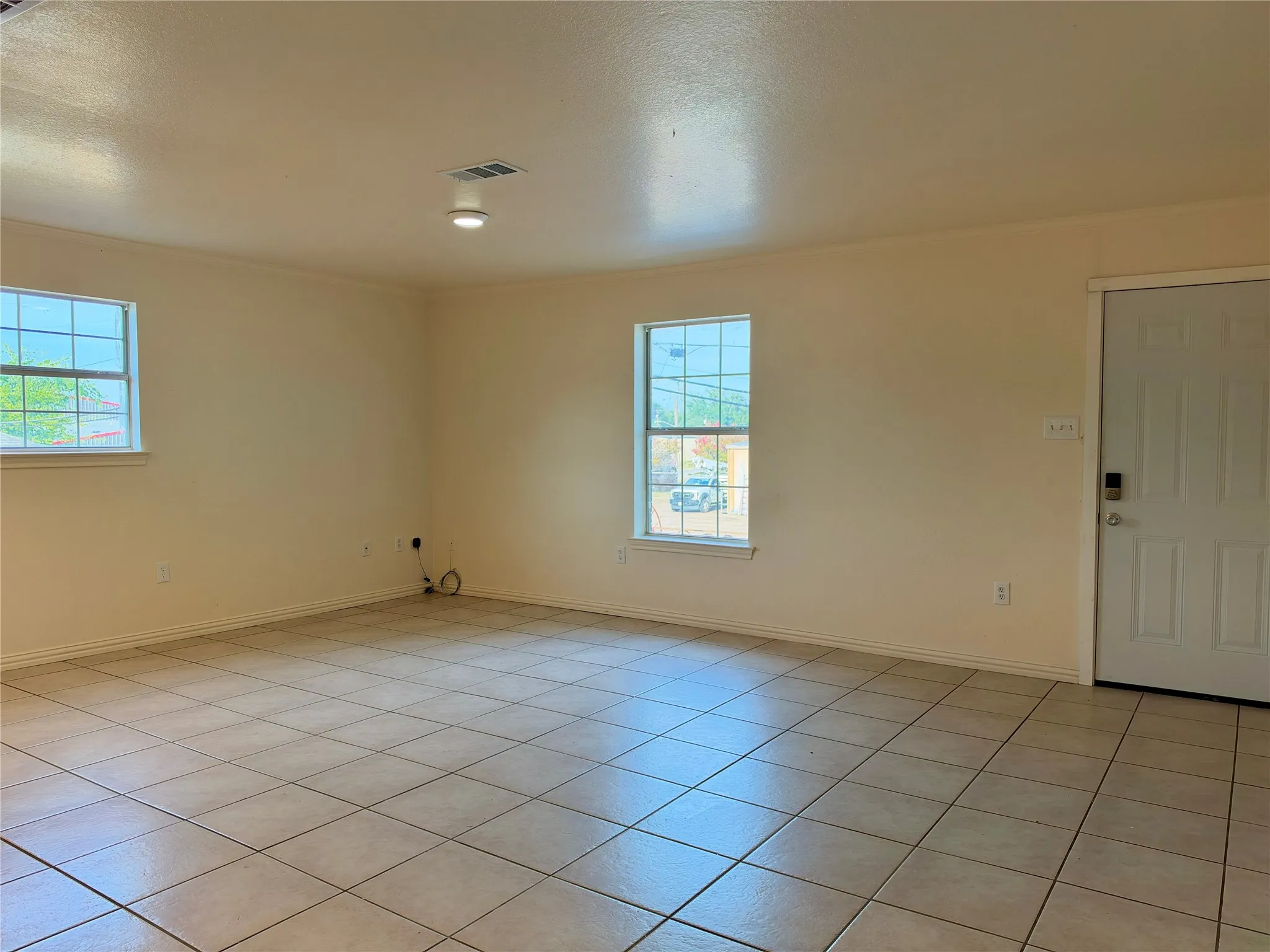 Tile flooring, two windows with sills, white trim, and a white entry door