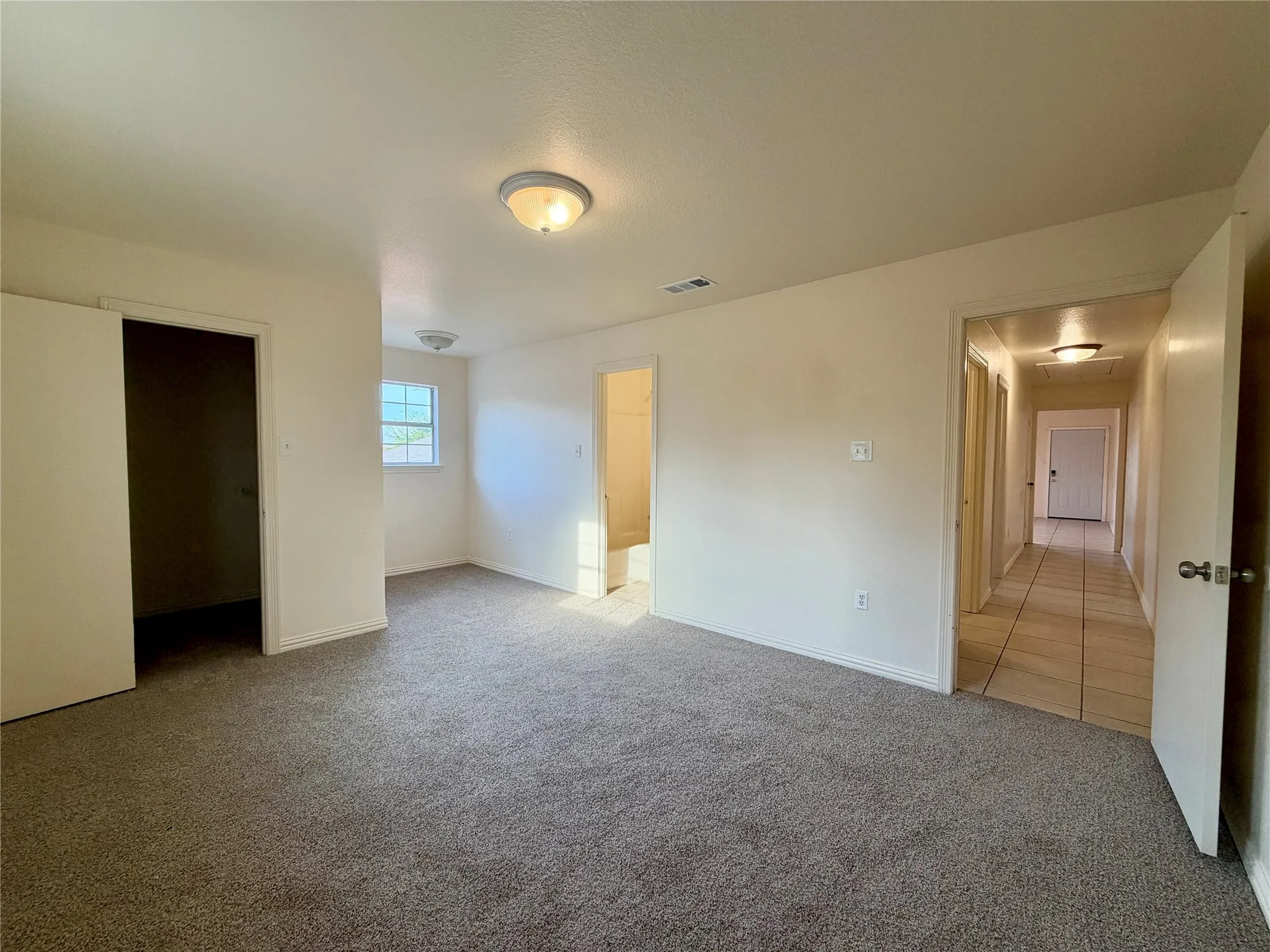 Carpeted room with a window, white walls, and a flush mount light fixture