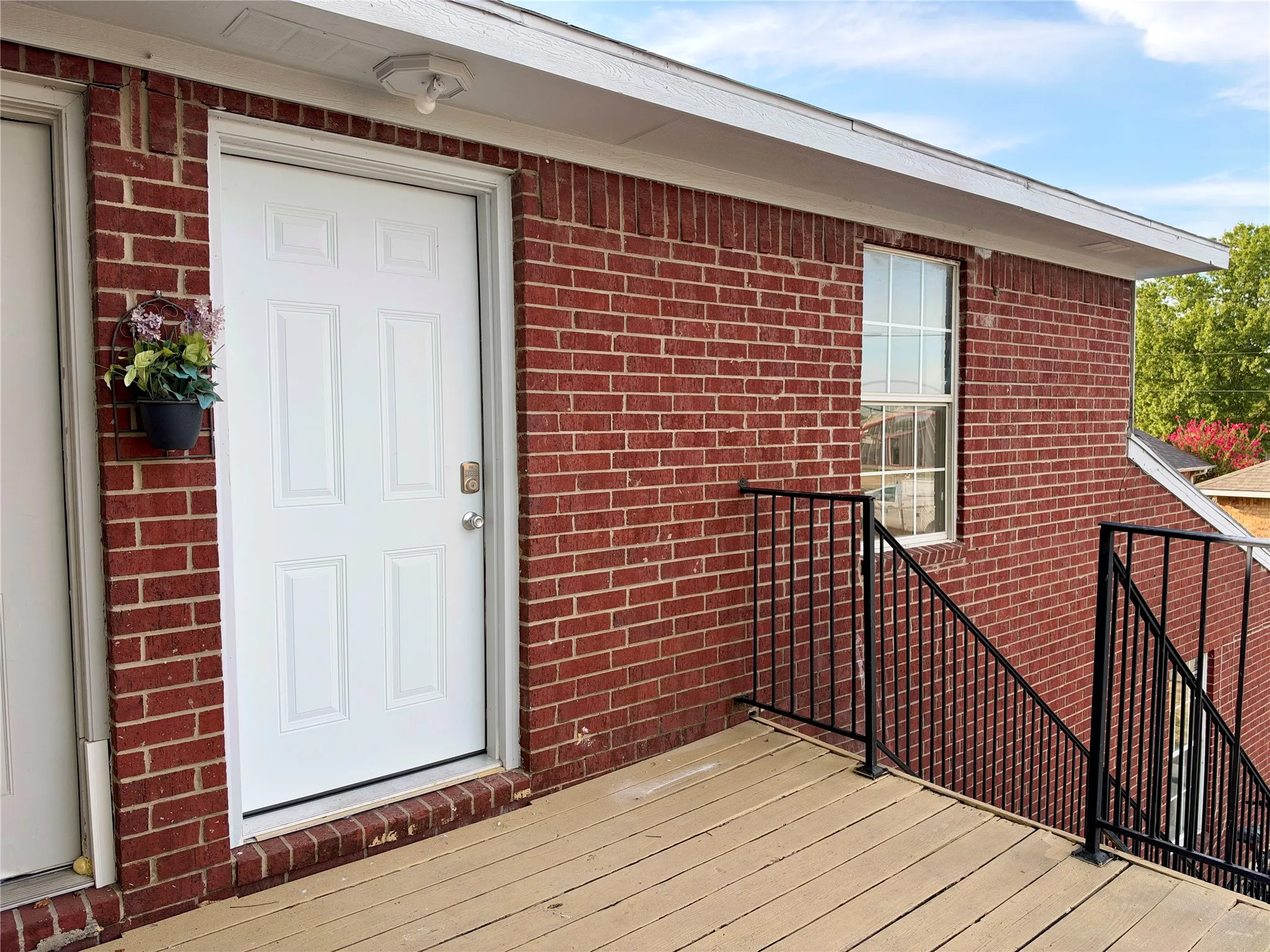 Red brick exterior with white trim, a multi-panel door, and a single-pane window