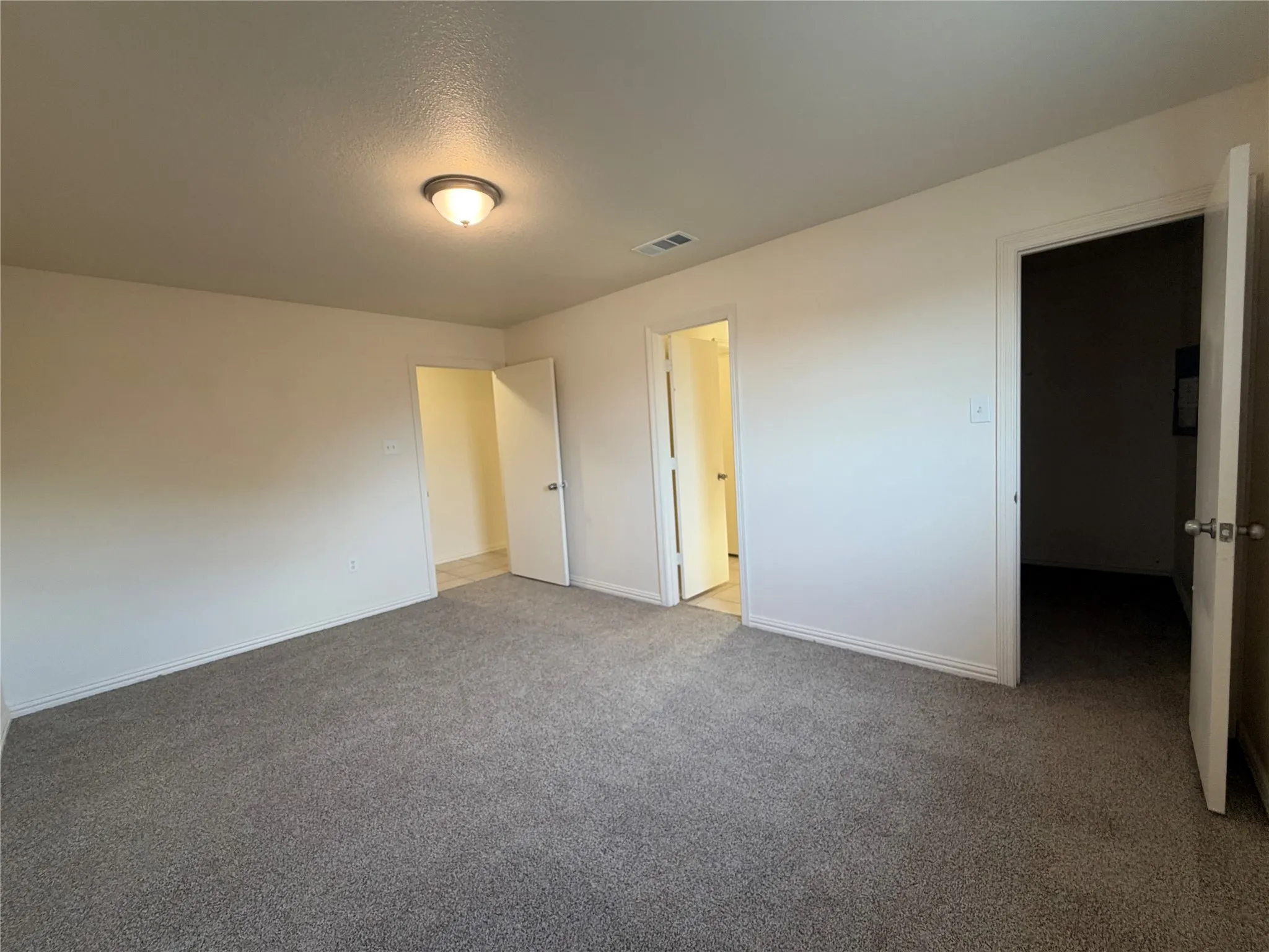Neutral wall tones with a textured ceiling finish, recessed lighting fixture, and gray carpeted flooring