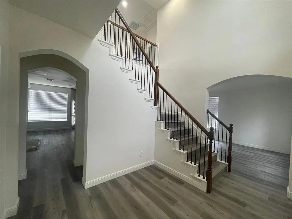 Entryway featuring a grand staircase with wrought iron balusters and wood-finish handrails