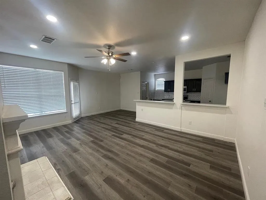 Wood-finish flooring, recessed lighting, ceiling fan, and a fireplace with a tiled hearth