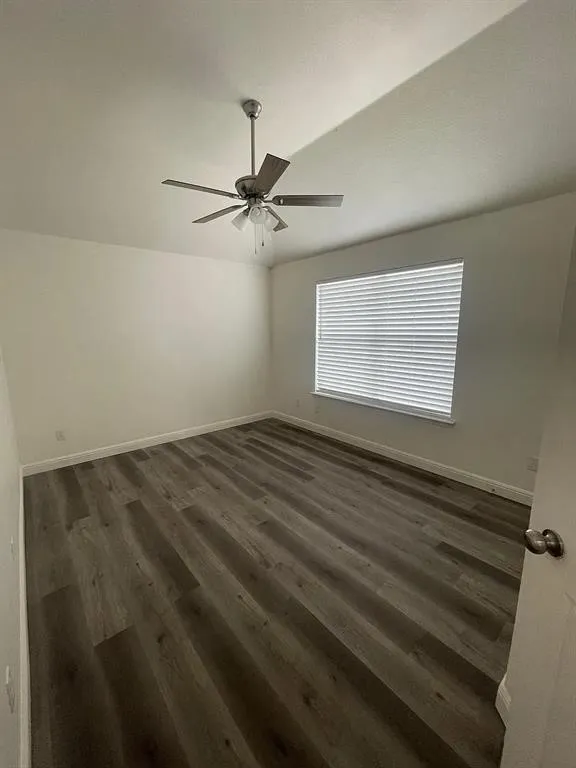 Wood-finish flooring, white walls, window with blinds, and a ceiling fan