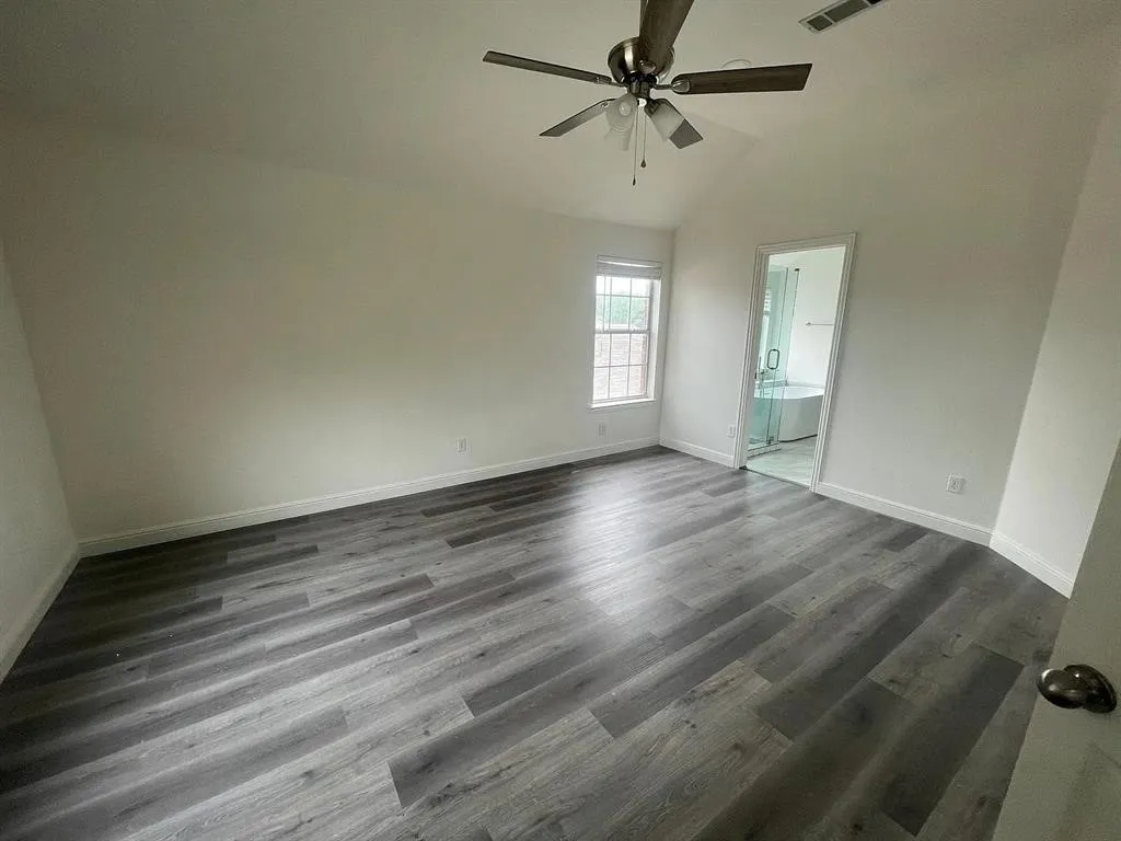 Wood-finish flooring, vaulted ceiling, ceiling fan, and a window with grid inserts