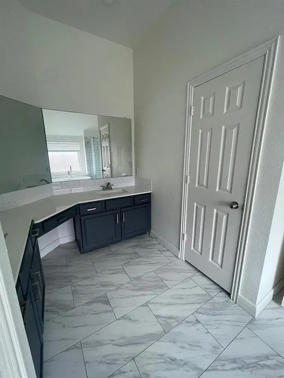 Spacious bathroom featuring a double vanity, white subway tile backsplash, and large-format tile flooring