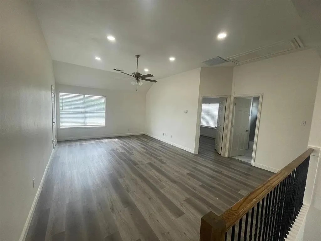 Vaulted ceiling with recessed lighting, wood-finish flooring, ceiling fan, and window with blinds