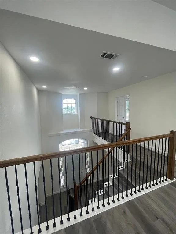 Two-story entry featuring wood-finish flooring, wrought iron spindles, wood handrails, and an arched window