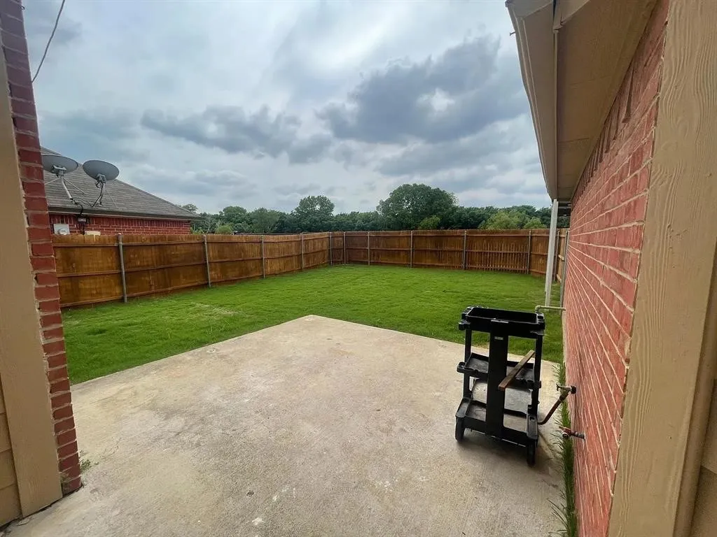 Fenced backyard with a concrete patio and a manicured lawn