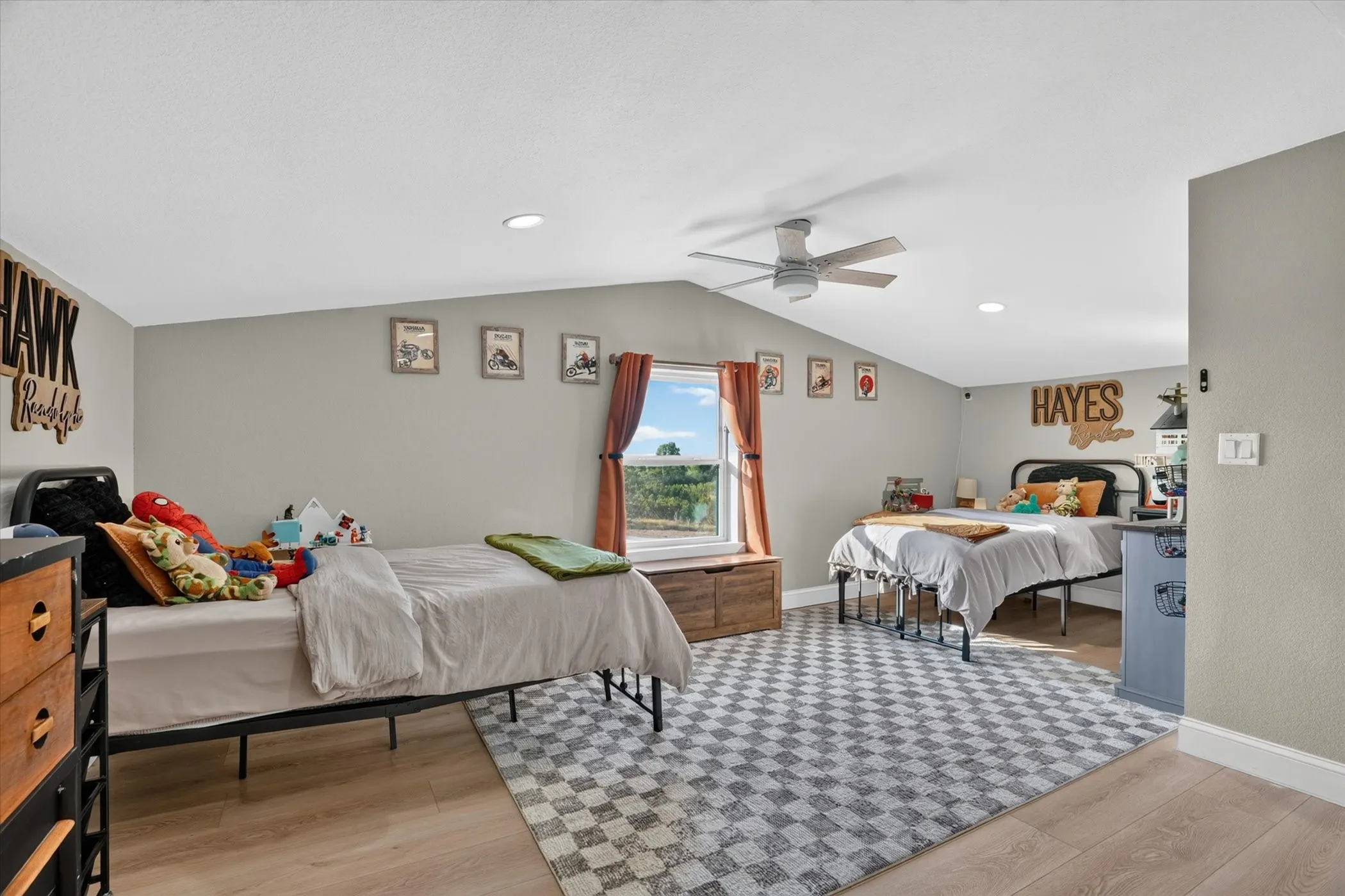 Vaulted ceiling, recessed lighting, wood-finish flooring, ceiling fan, and window with exterior scenery