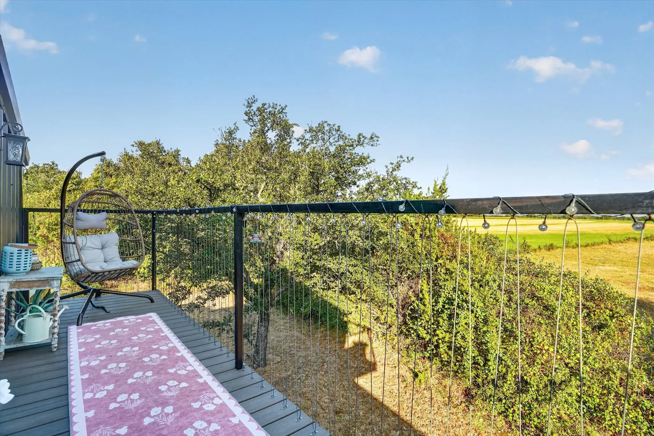 Deck with composite wood-finish flooring, black metal railings, and a prominent treed backdrop
