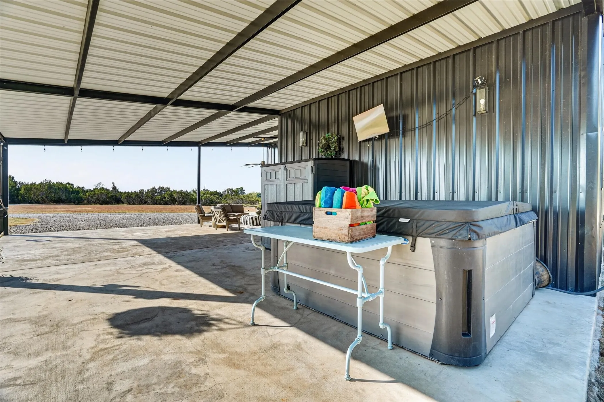 Covered patio featuring a hot tub, concrete flooring, and metal wall siding