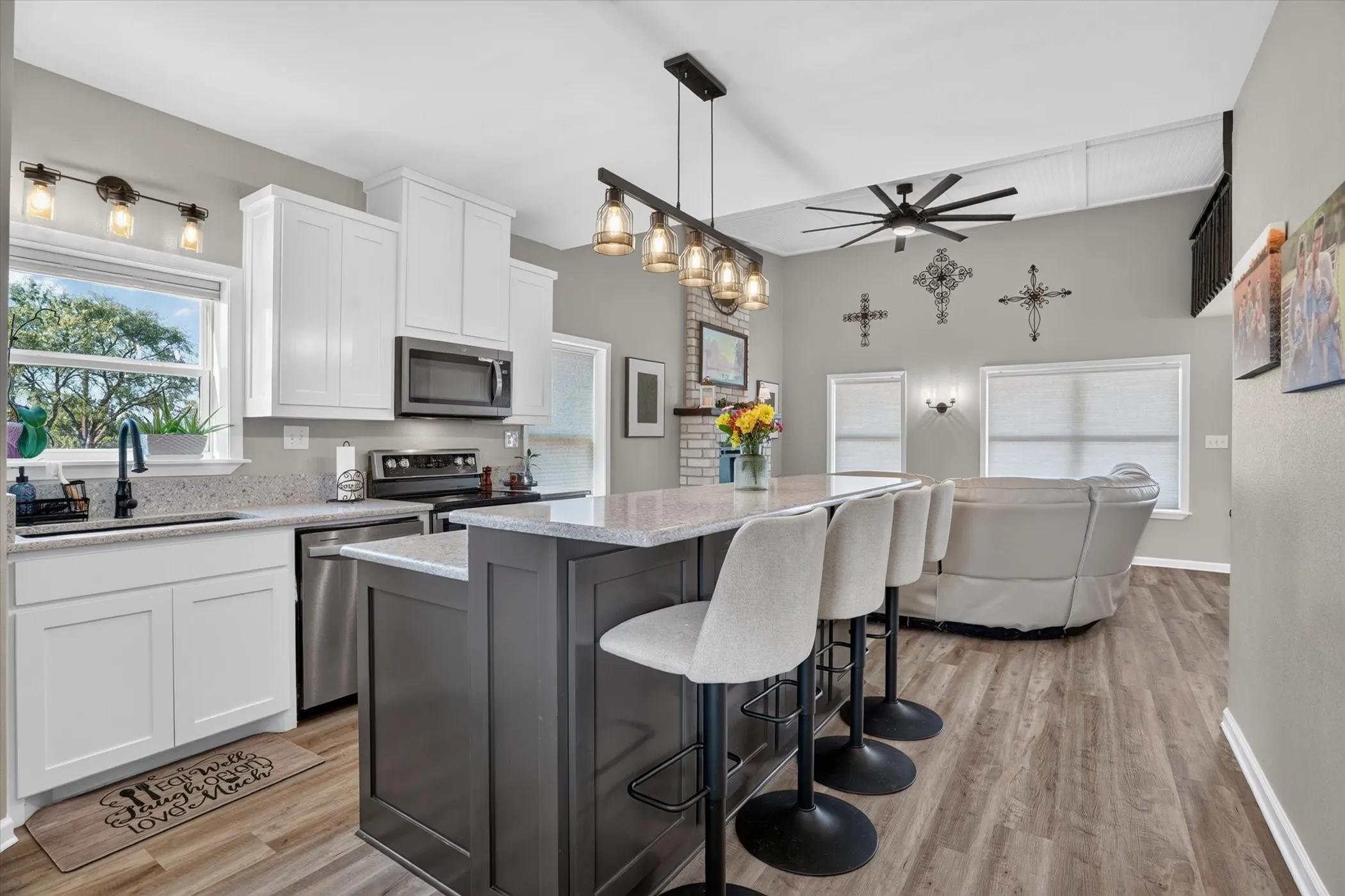 Kitchen with white cabinetry, light-toned countertops, and a gray island with seating
