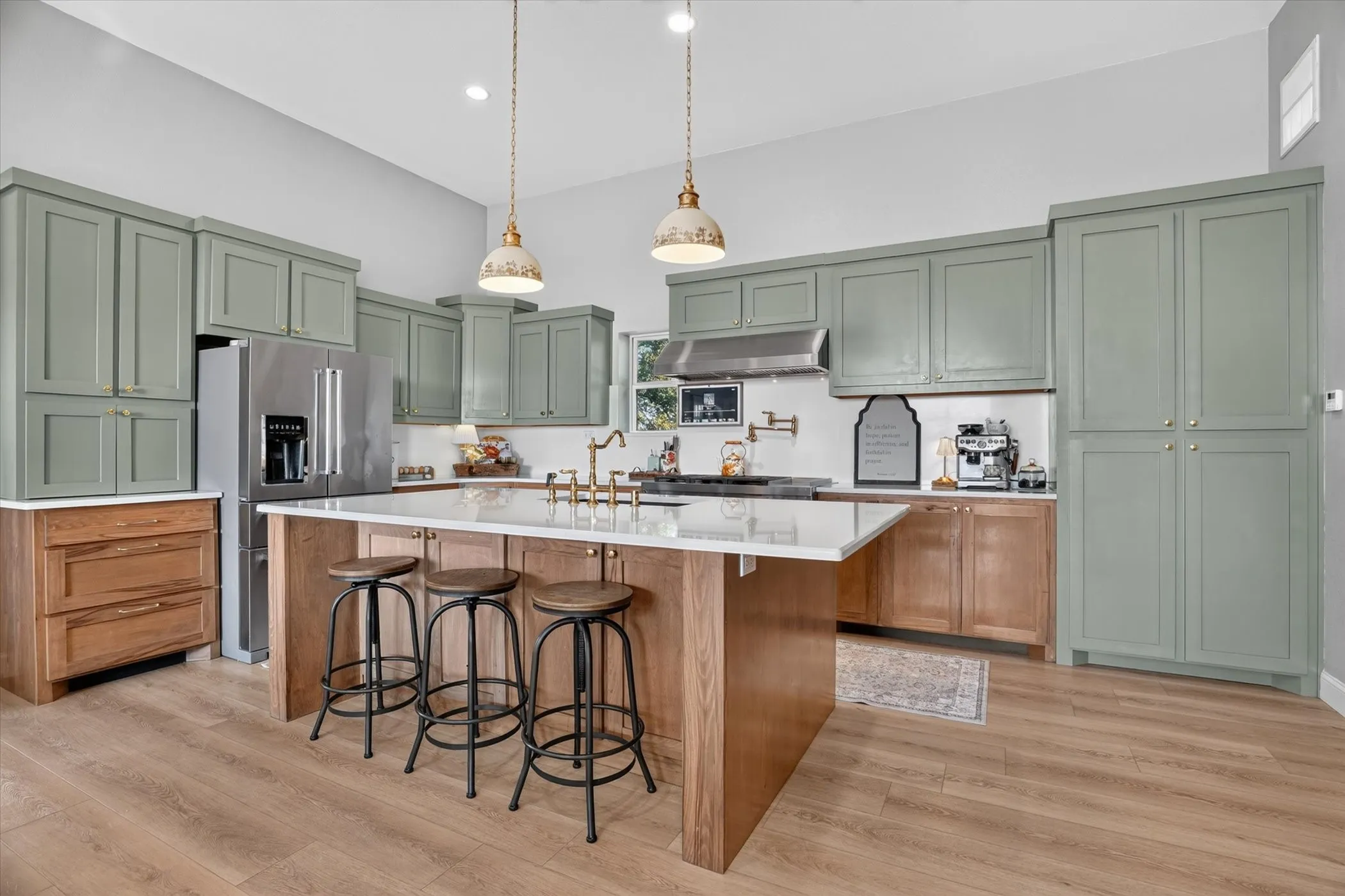 Kitchen featuring sage green cabinetry, stainless steel appliances, a center island with seating, a white solid surface countertop, and wood-finish flooring