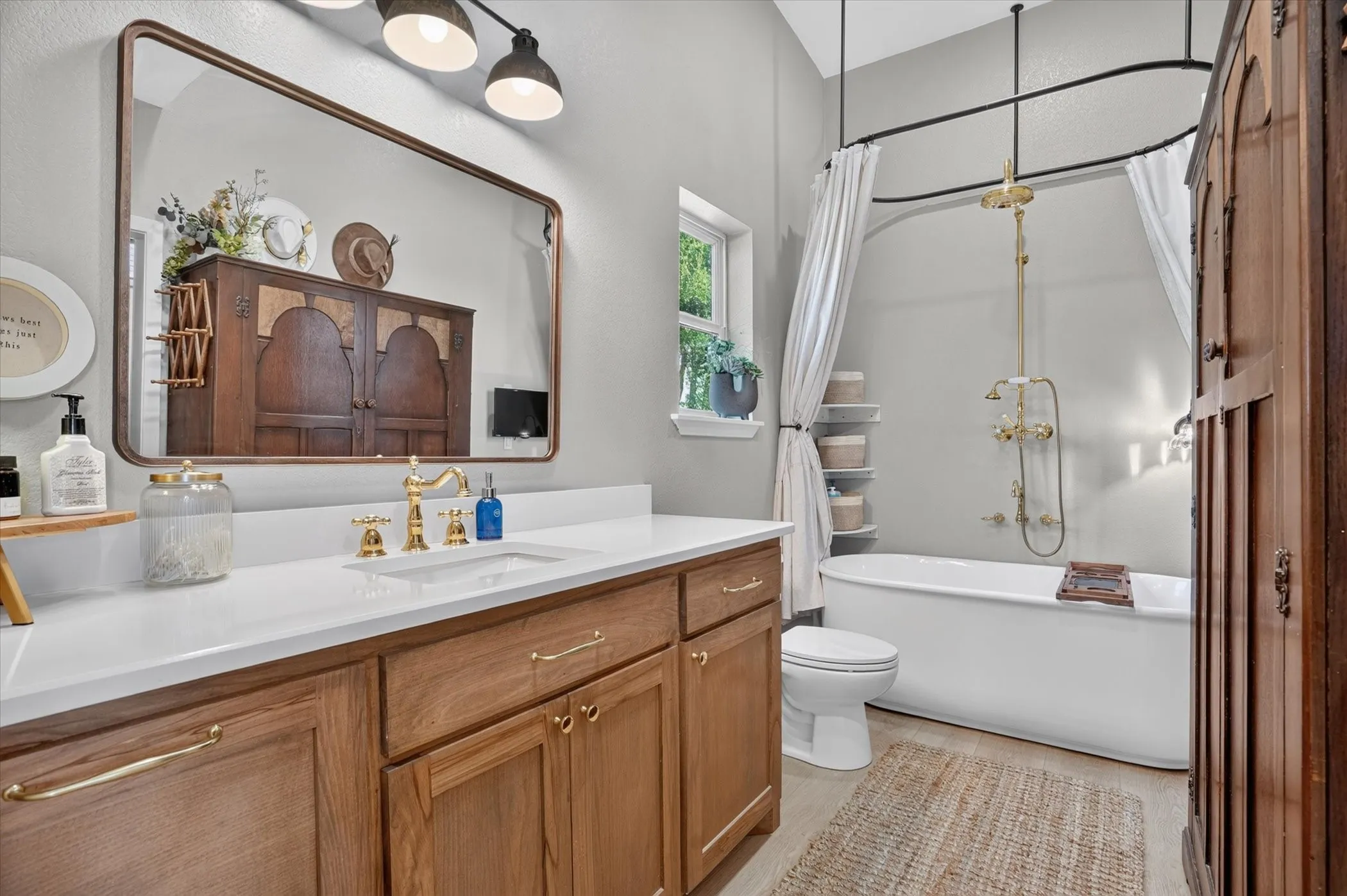 Wood-finish vanity with gold-tone hardware, rectangular undermount sink, and white countertop