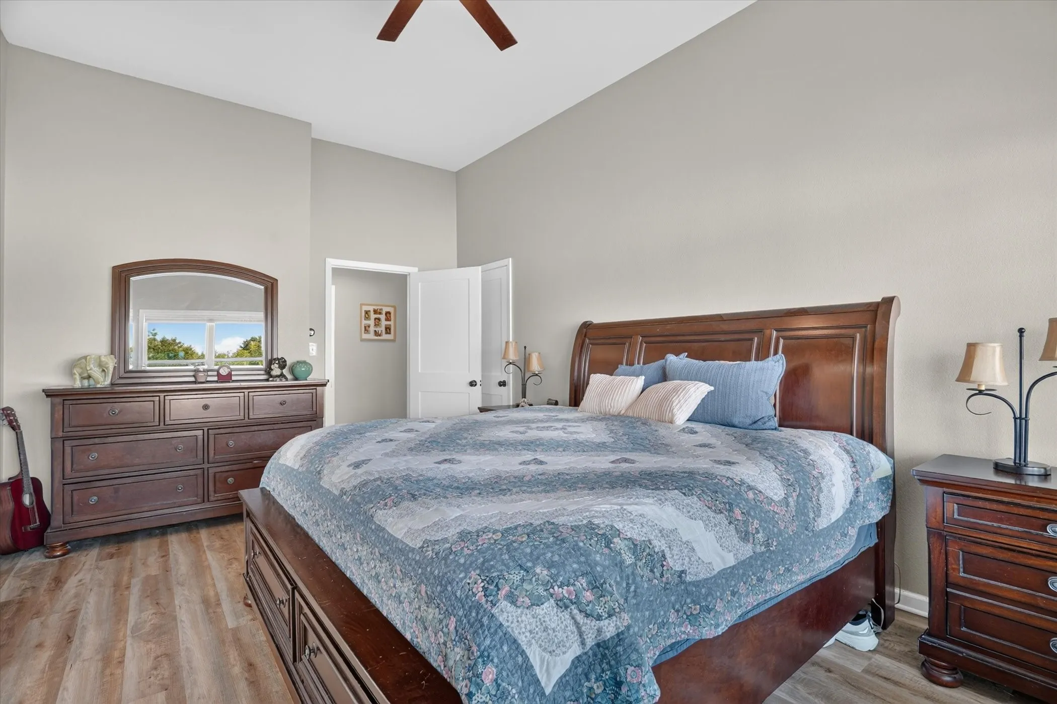 Vaulted ceiling room featuring wood-finish flooring, a window with exterior scenery, and a ceiling fan