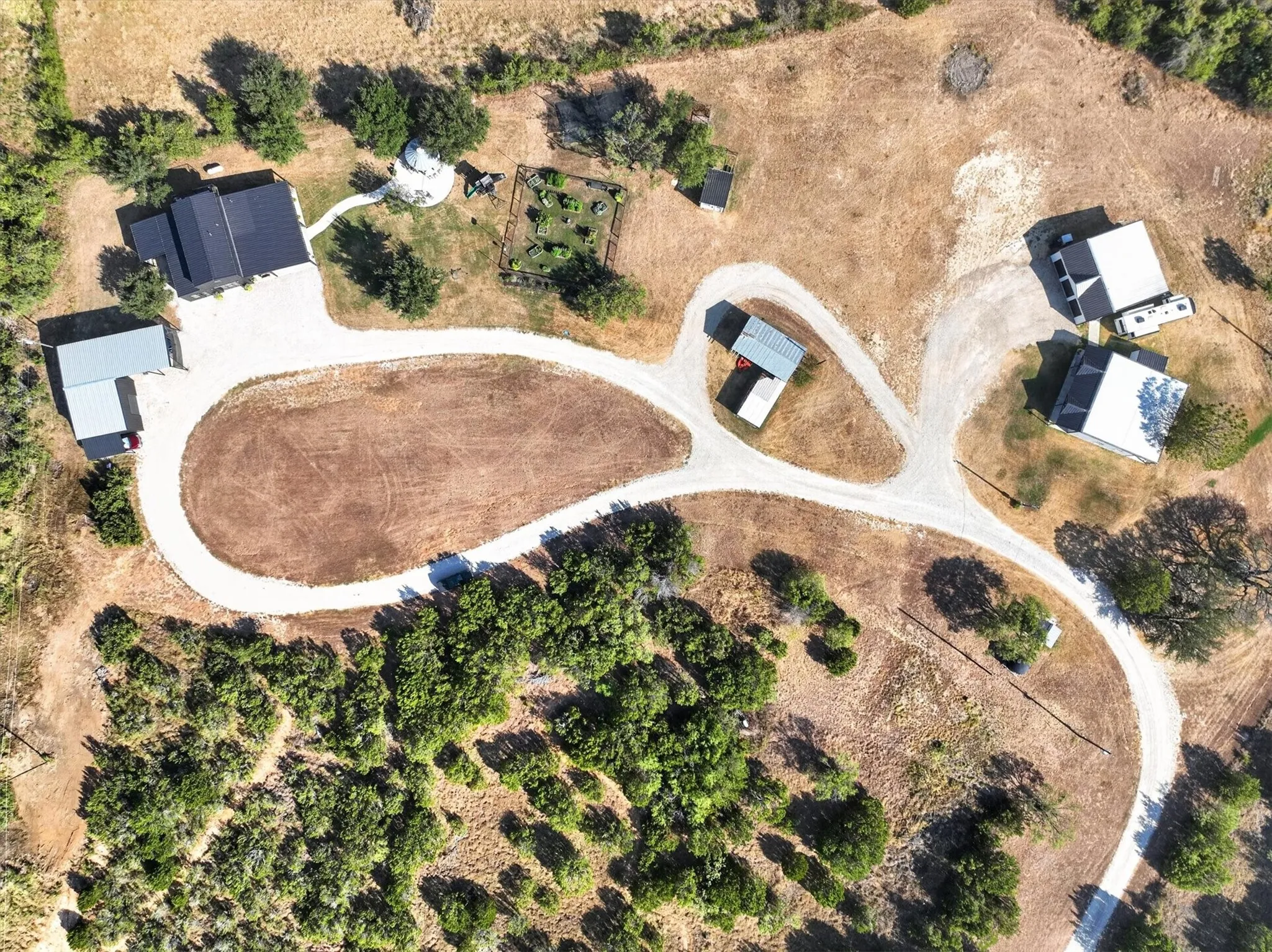 Multiple structures on an expansive property featuring gravel driveways and mature trees